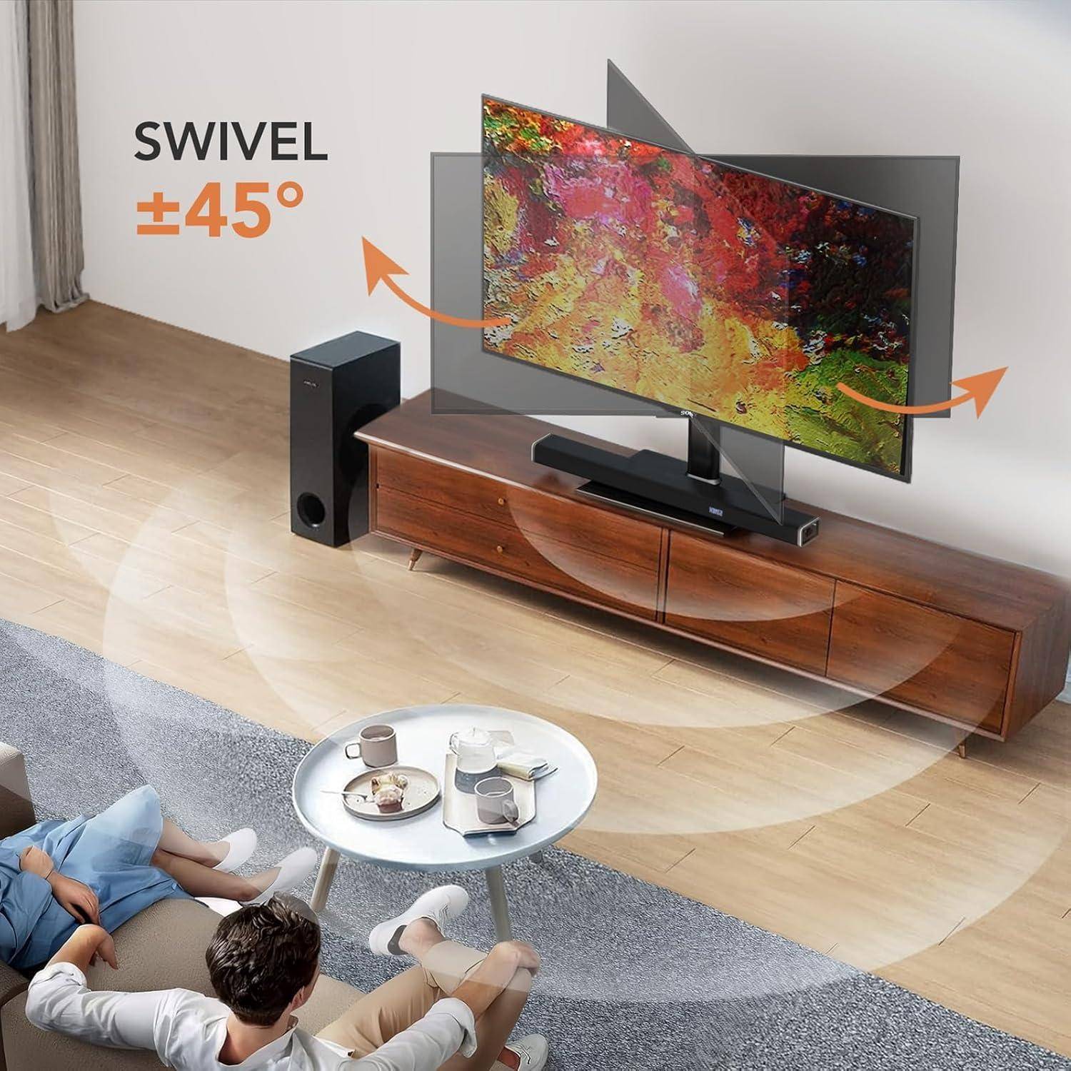 Fernsehgerät auf einem Holzständer dreht sich 45 Grad nach links oder rechts. Zwei Personen sitzen auf einem Sofa mit Kaffee auf einem Tisch und schauen auf den Bildschirm.