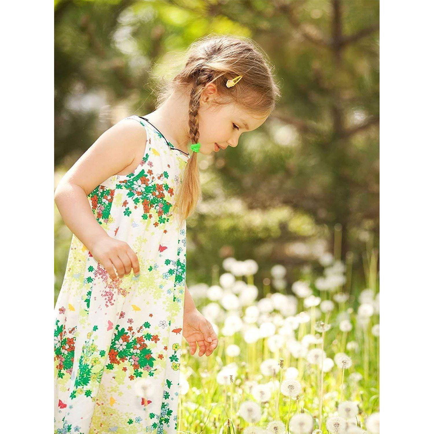 Ein junges Mädchen mit geflochtenen Haaren, gekleidet in ein Blumenkleid, steht inmitten weißer Pusteblumen in einem sonnendurchfluteten Garten und blickt auf die Blumen hinab.