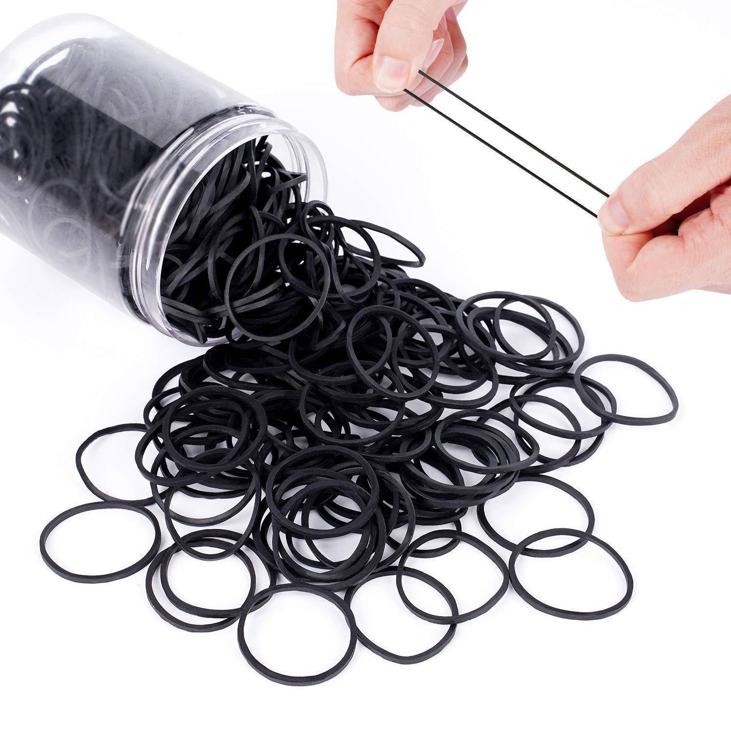 Eine Hand nimmt zwei schwarze Gummibänder aus einem verschütteten Behälter mit elastischen Bändern und demonstriert dabei Organisation und Zugänglichkeit.