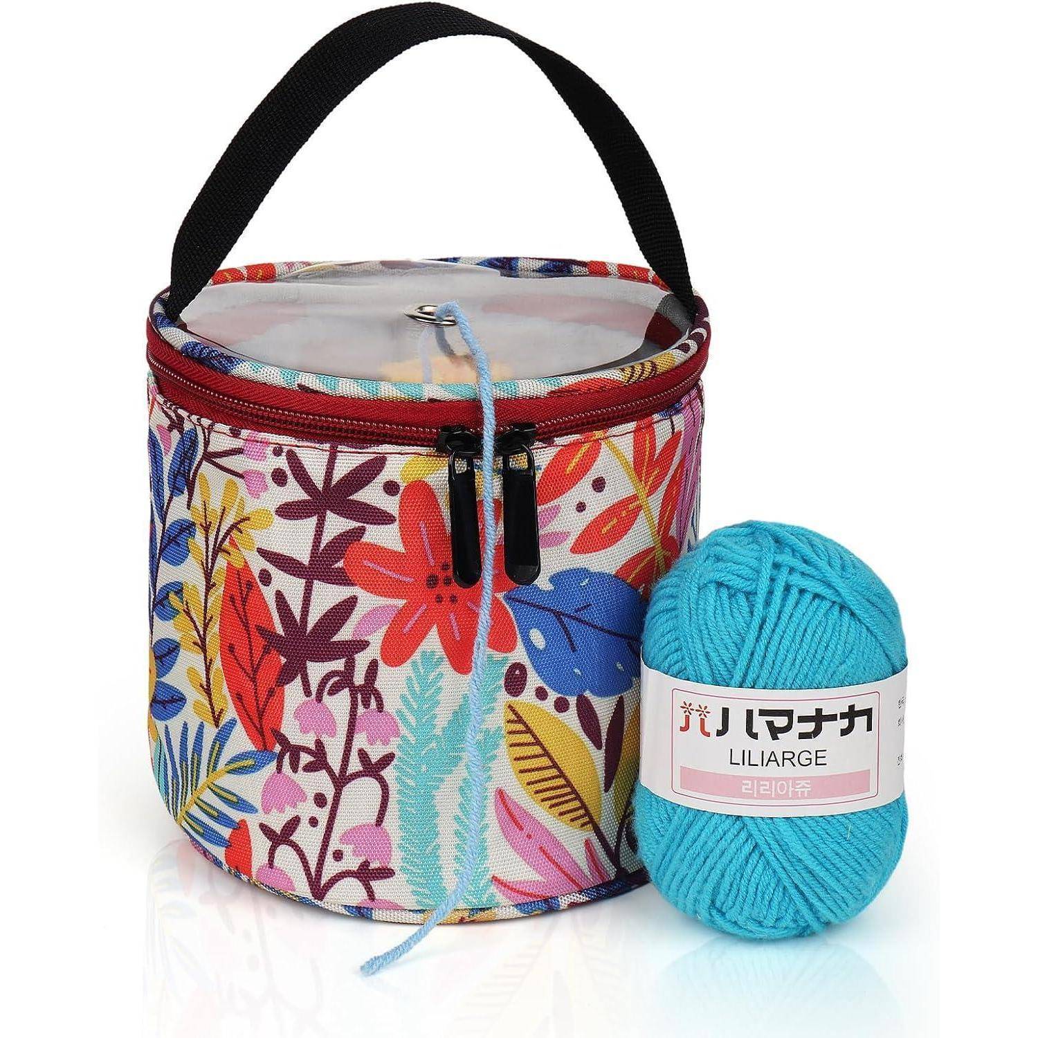 Eine bunte gestrickte Tasche mit einem Blumenmuster und schwarzem Griff wird von einer Wollkugel in Blau begleitet, die mit 'Liliarge' beschriftet ist.