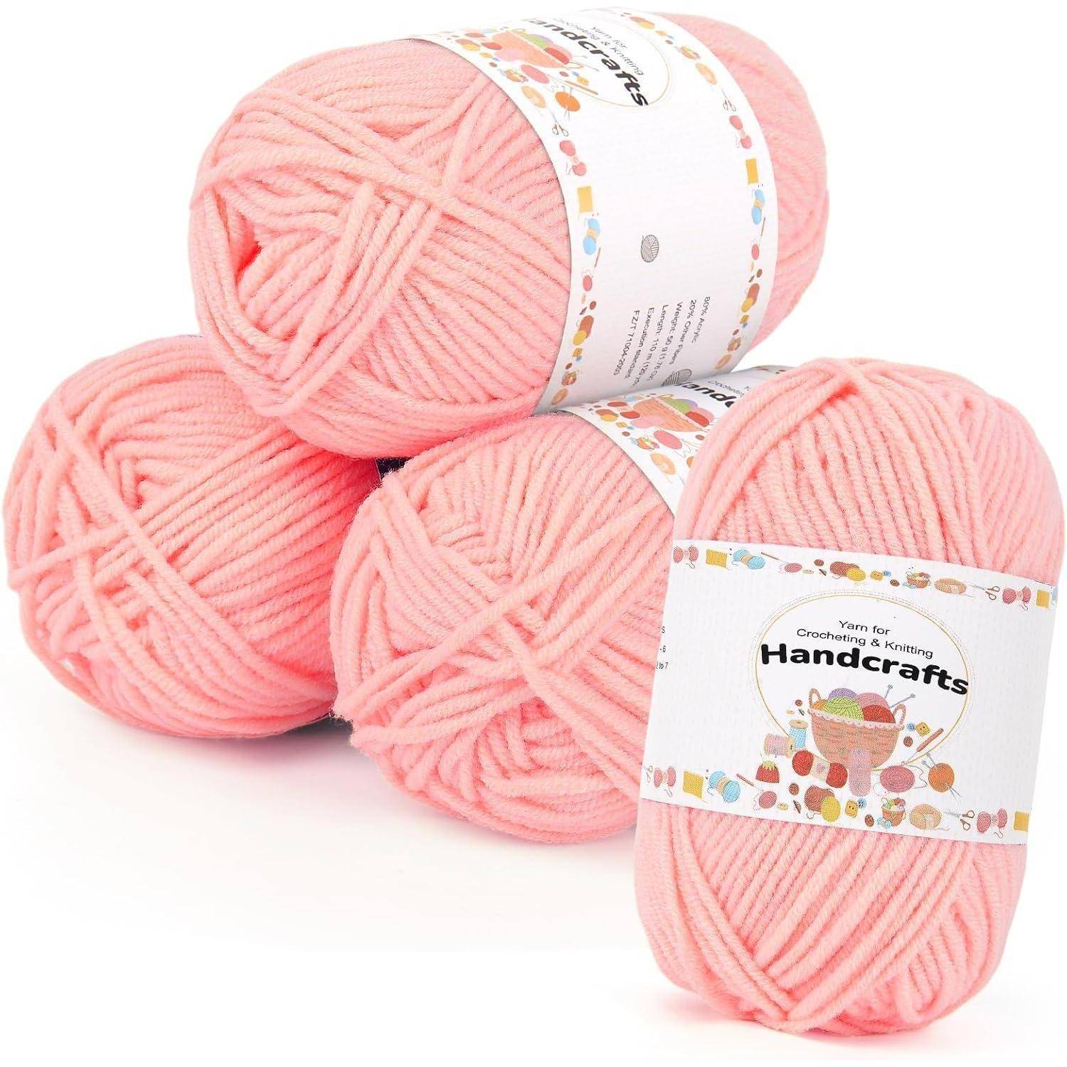 Drei Knäuel weiches rosa Garn mit der Aufschrift 'HandCrafts' zum Stricken und Häkeln, in einer Pyramidenform angeordnet.