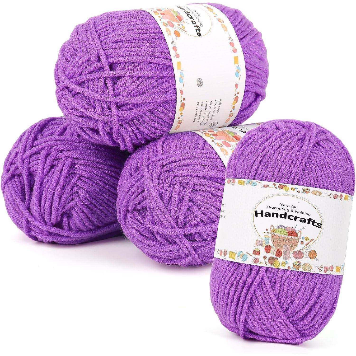 Drei Knäuel lila Garn mit der Bezeichnung 'HandCrafts', die in einem dreieckigen Stapel angeordnet sind und die Textur und leuchtende Farbe des Garns präsentieren.