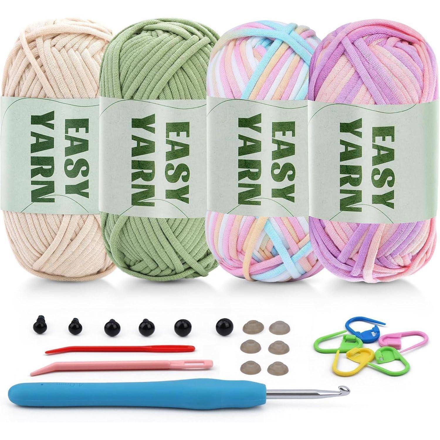 Vier Knäuel 'Easy Yarn' in Beige, Grün, Multicolor und Lila mit Häkelwerkzeugen und -zubehör, einschließlich Häkelnadeln und Markierern.