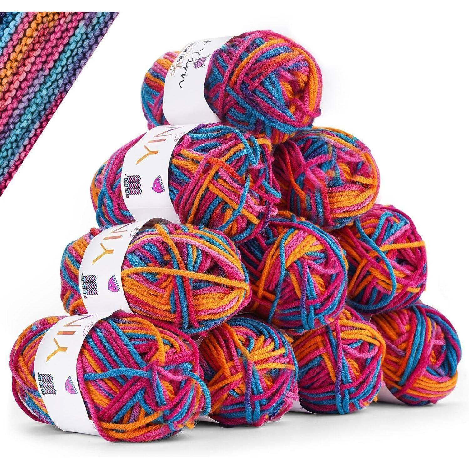 Bunte Garnknäuel, in einer Pyramidenform gestapelt, mit einer Nahaufnahme, die Regenbogentöne von Rosa, Orange, Blau und Gelb ineinander verwoben zeigt.