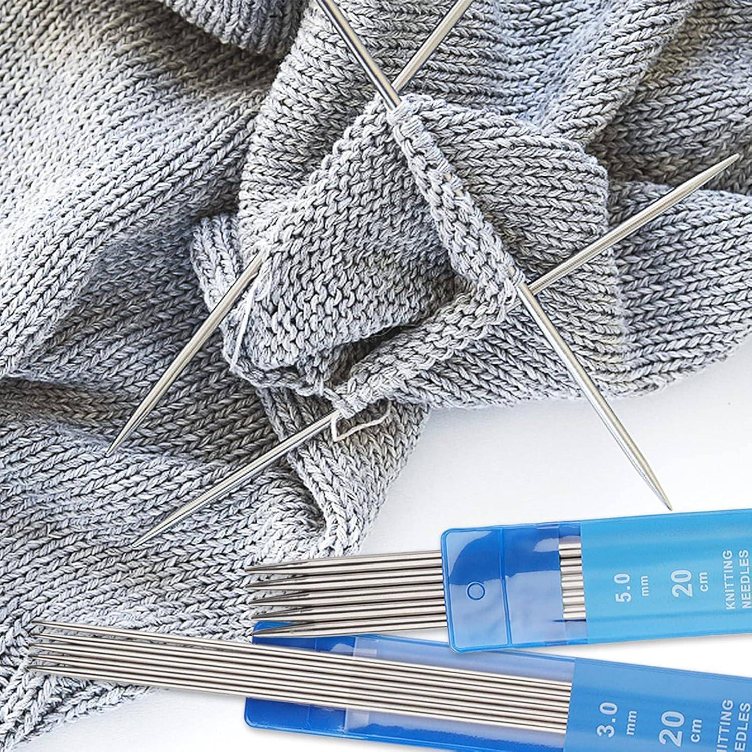 Strickprojekt mit grauer Wolle und Nadelspielnadeln, daneben ein Etui mit Stricknadeln in verschiedenen Größen.