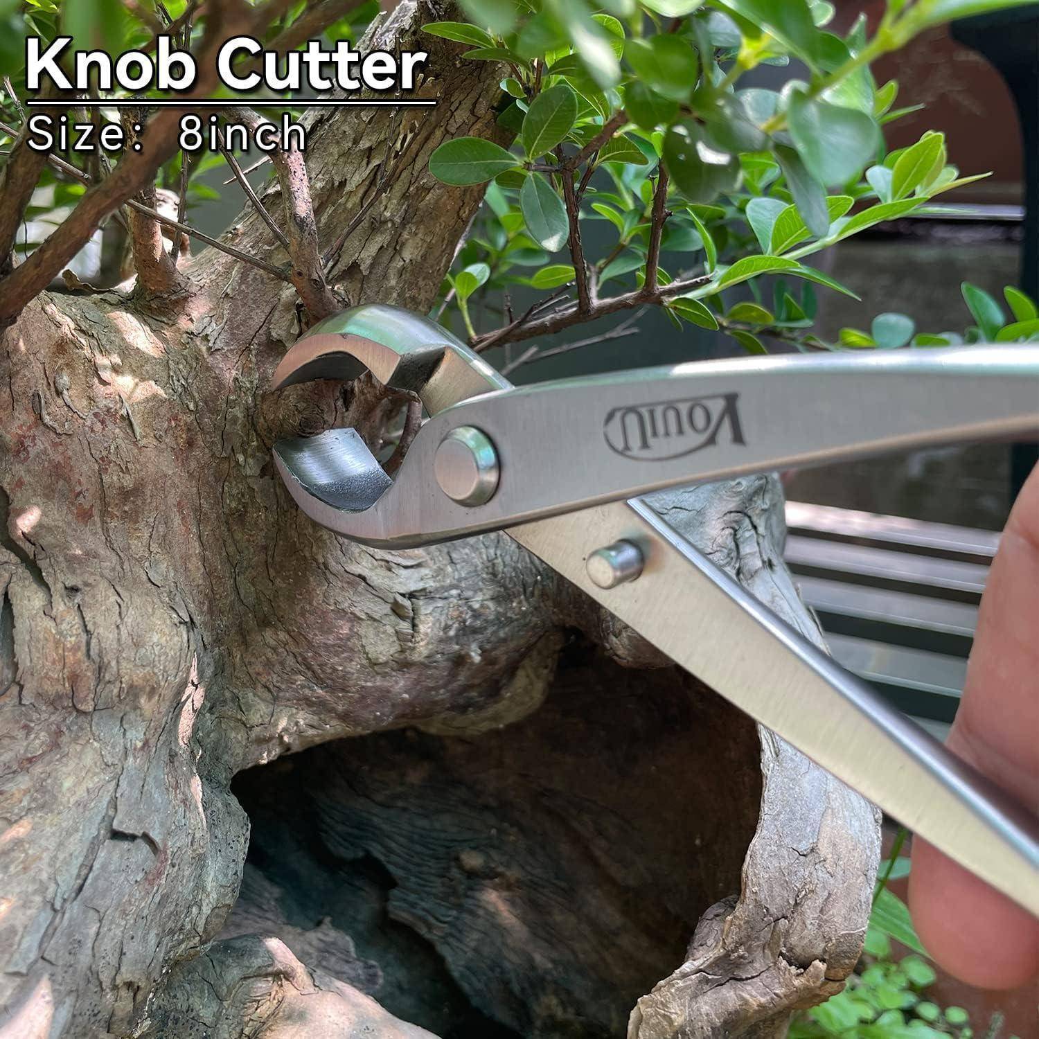Eine Nahaufnahme einer Hand, die einen 20-Zentimeter-Astschneider verwendet, um einen Bonsai-Baumzweig zu beschneiden. Das Metallwerkzeug ist in der Nähe des Baumstamms positioniert.