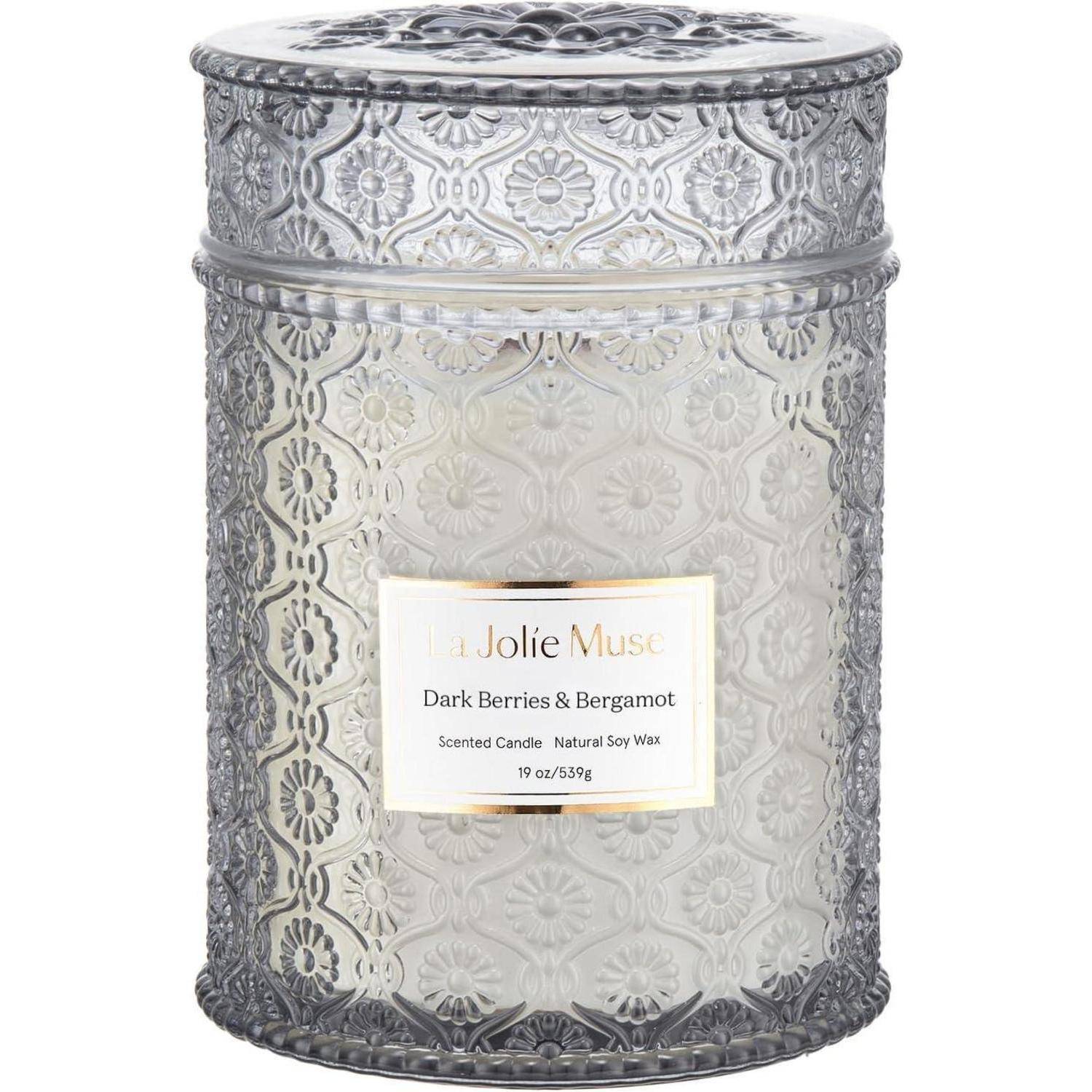 Ein verzierter Glaskerzenbecher mit Blumenmustern, beschriftet mit 'La Jolie Muse, Dunkle Beeren & Bergamotte, Duftkerze, Natürliches Sojawachs, 19 oz'.