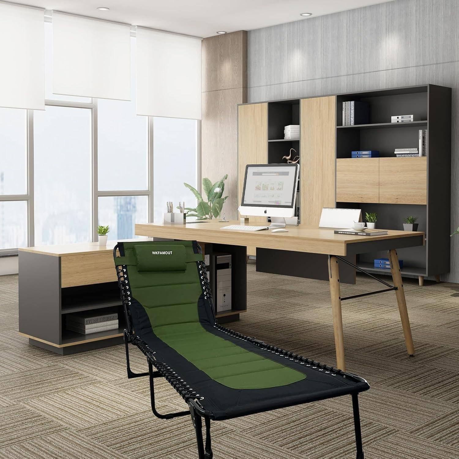 Ein modernes Büro mit einem Holzschreibtisch, Computer und einem ergonomischen Stuhl. Große Fenster sorgen für natürliches Licht. Ein Loungestuhl ist zu sehen.