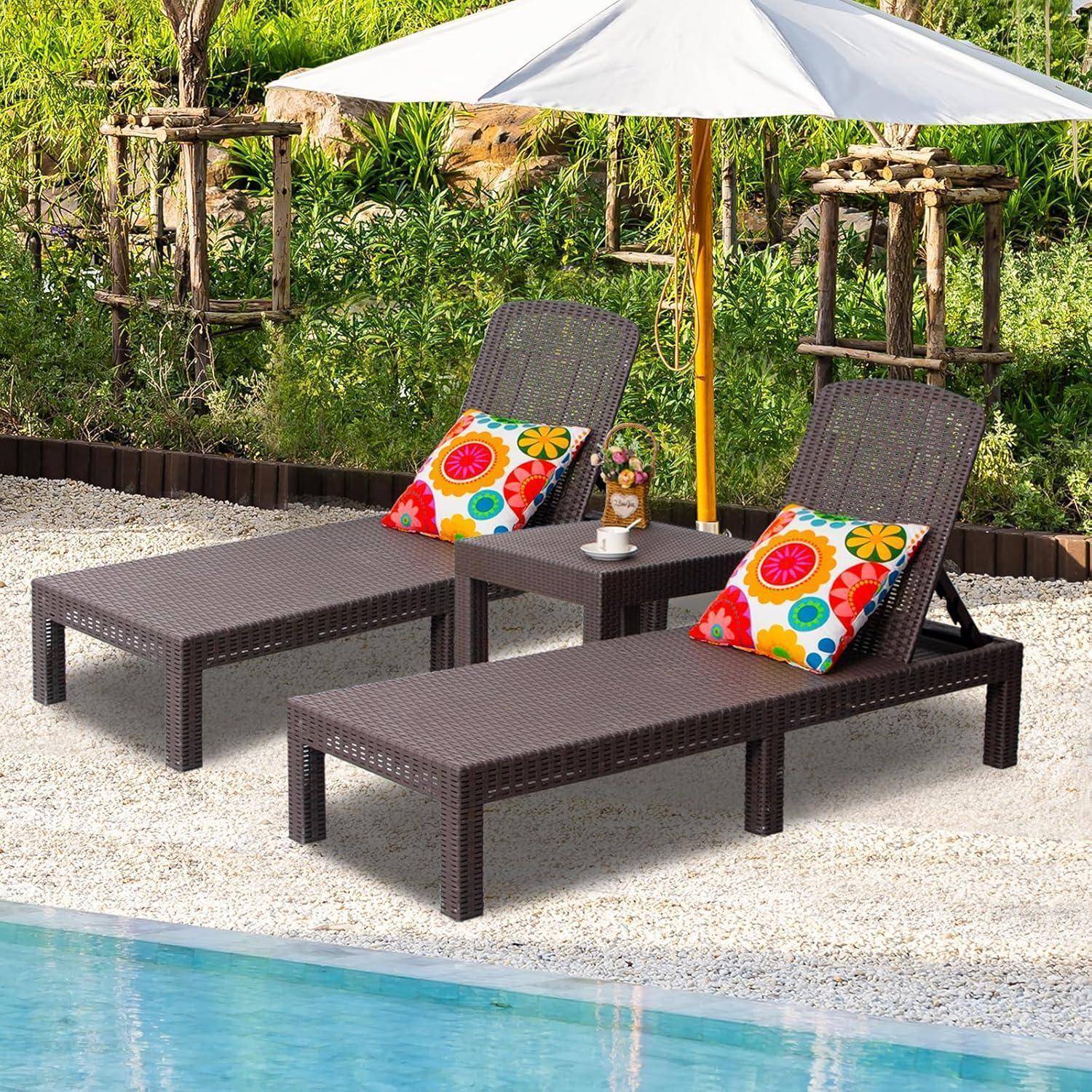 Zwei Korbsessel mit bunten Kissen sind unter einem Sonnenschirm am Poolrand platziert, umgeben von Grünpflanzen und dekorativen Pflanzgefäßen.