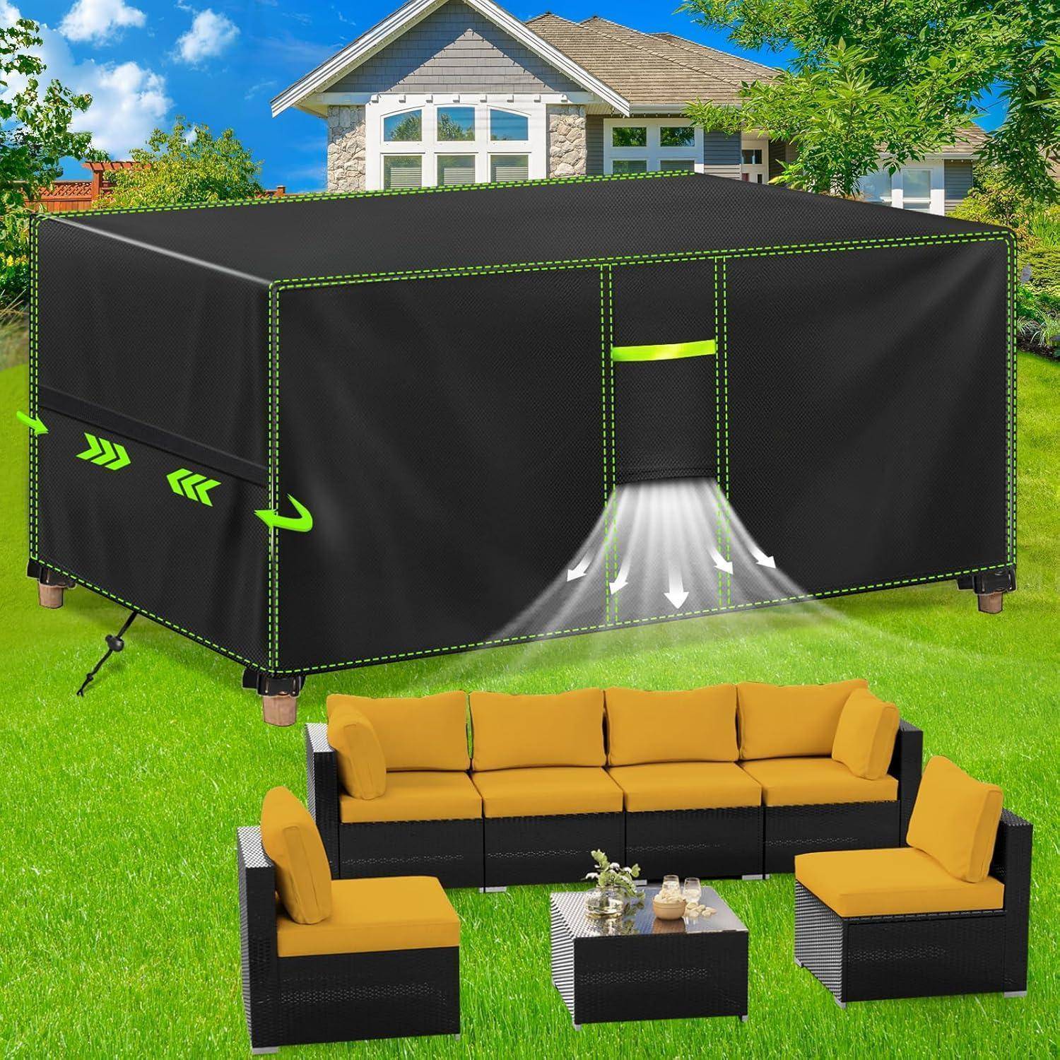 Ein großes, schwarzes Outdoor-Zelt steht auf einer Rasenfläche mit einem modernen Haus im Hintergrund. Davor befindet sich eine Sitzgruppe mit gelben Kissen.