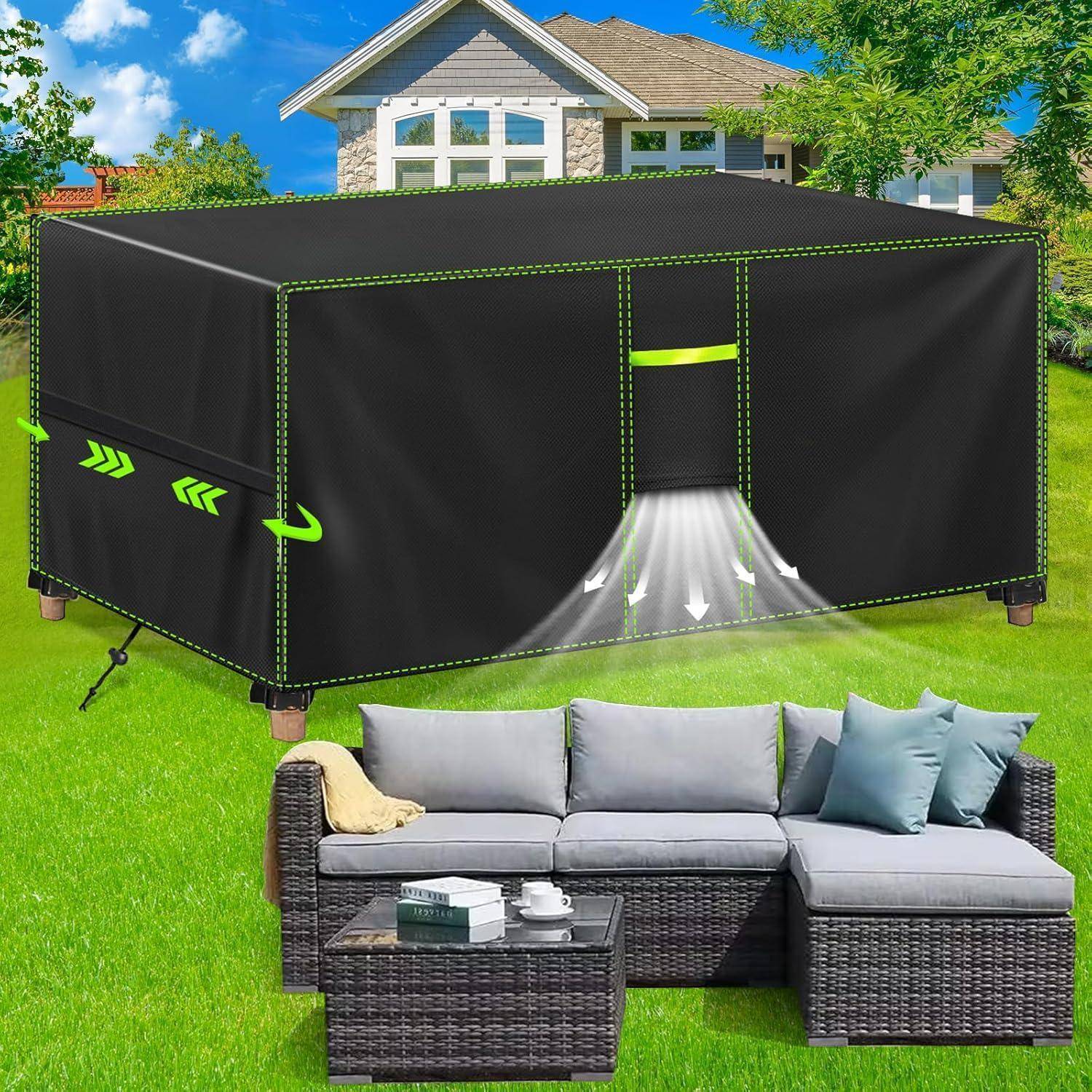 Eine Terrasse im Freien mit einer grauen Sofagarnitur vor einer großen, schwarzen rechteckigen Abdeckung, höchstwahrscheinlich eine Grillabdeckung, in der Nähe eines modernen Hauses und eines grünen Rasens.