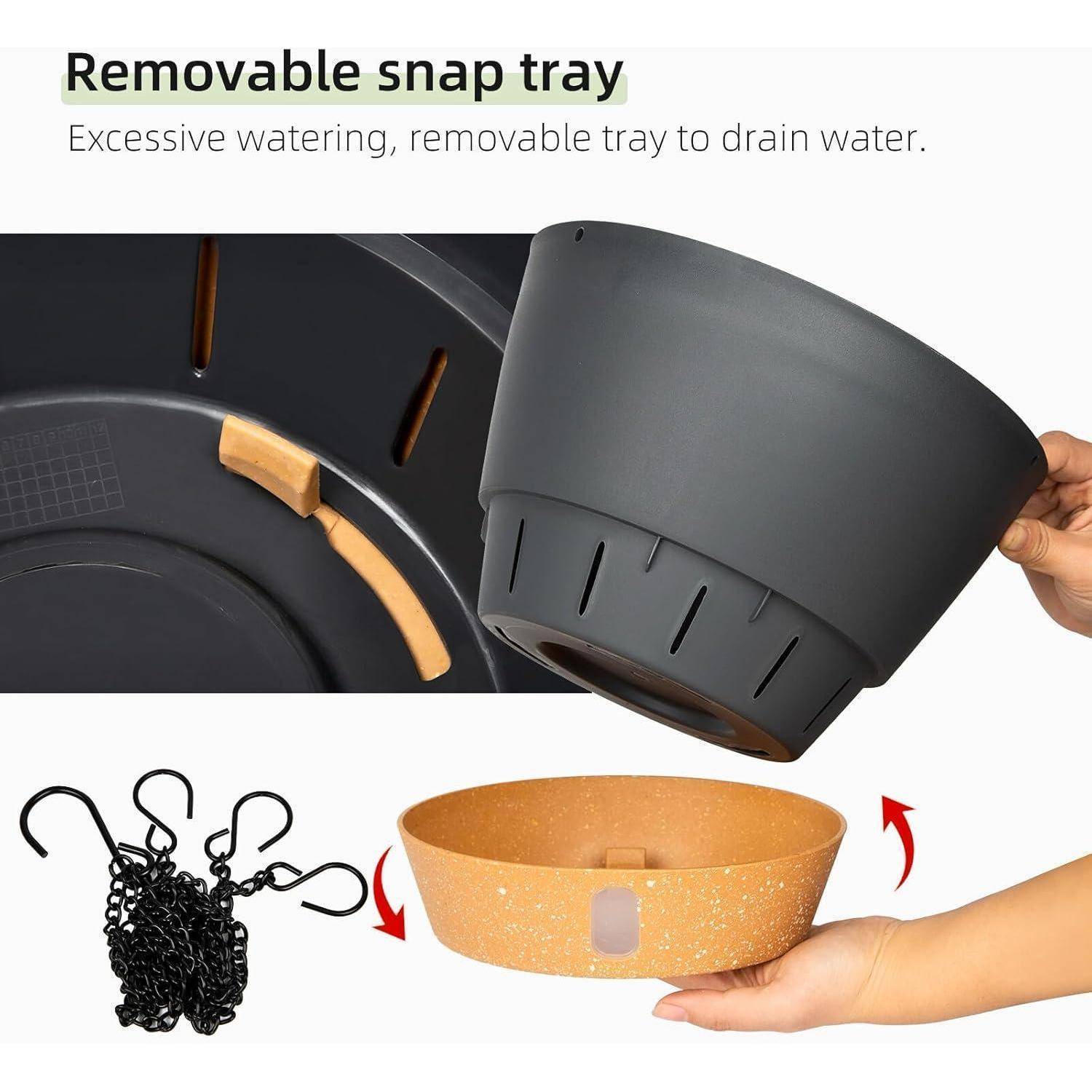 Eine Hand, die einen schwarzen Blumentopf mit einem herausnehmbaren Auffangbecken zum Ableiten von Wasser hält. Haken und eine Kette sind zu sehen, um den Topf aufzuhängen.