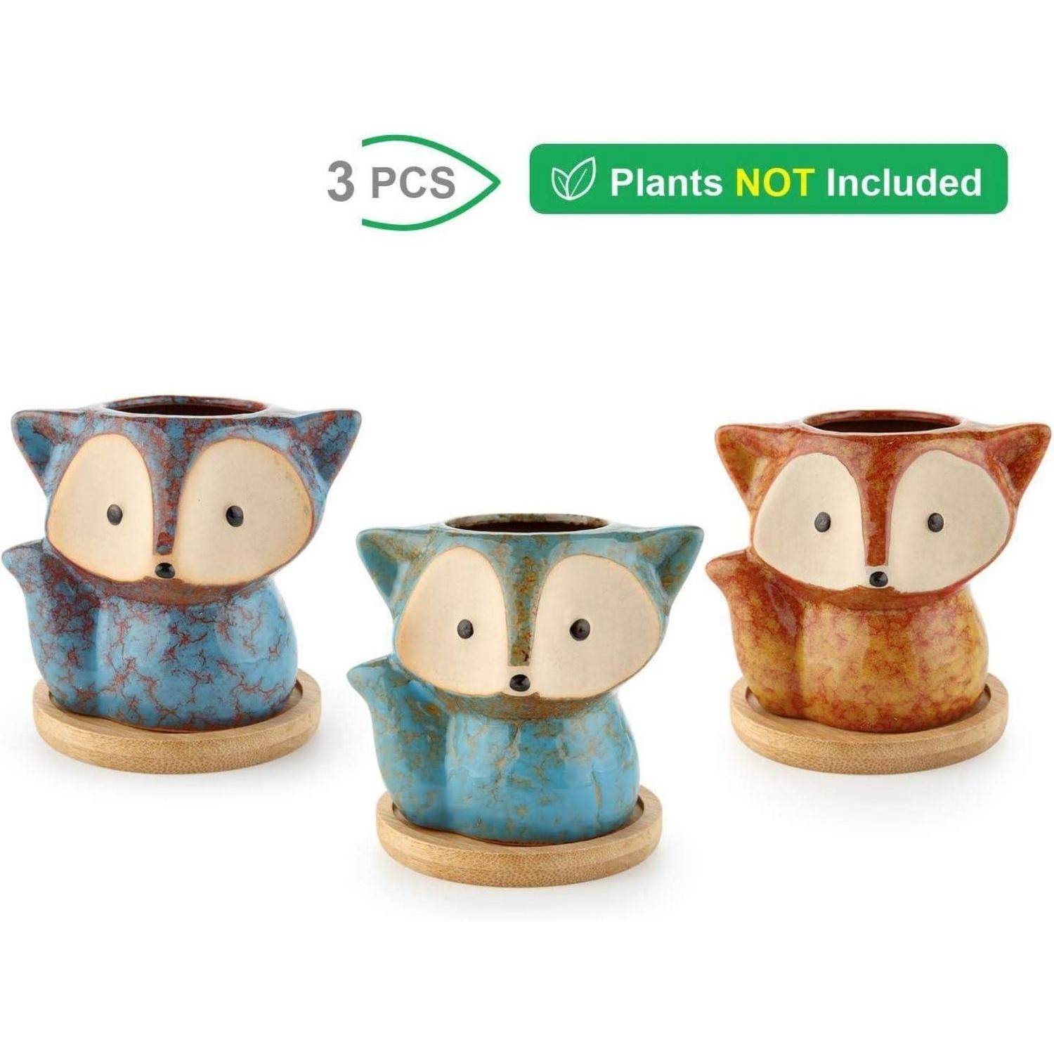 Drei Keramik-Pflanzentöpfe in Fuchsform in Blau, Petrol und Braun auf Holzbasen. Text: '3 STK. Pflanzen NICHT enthalten'.