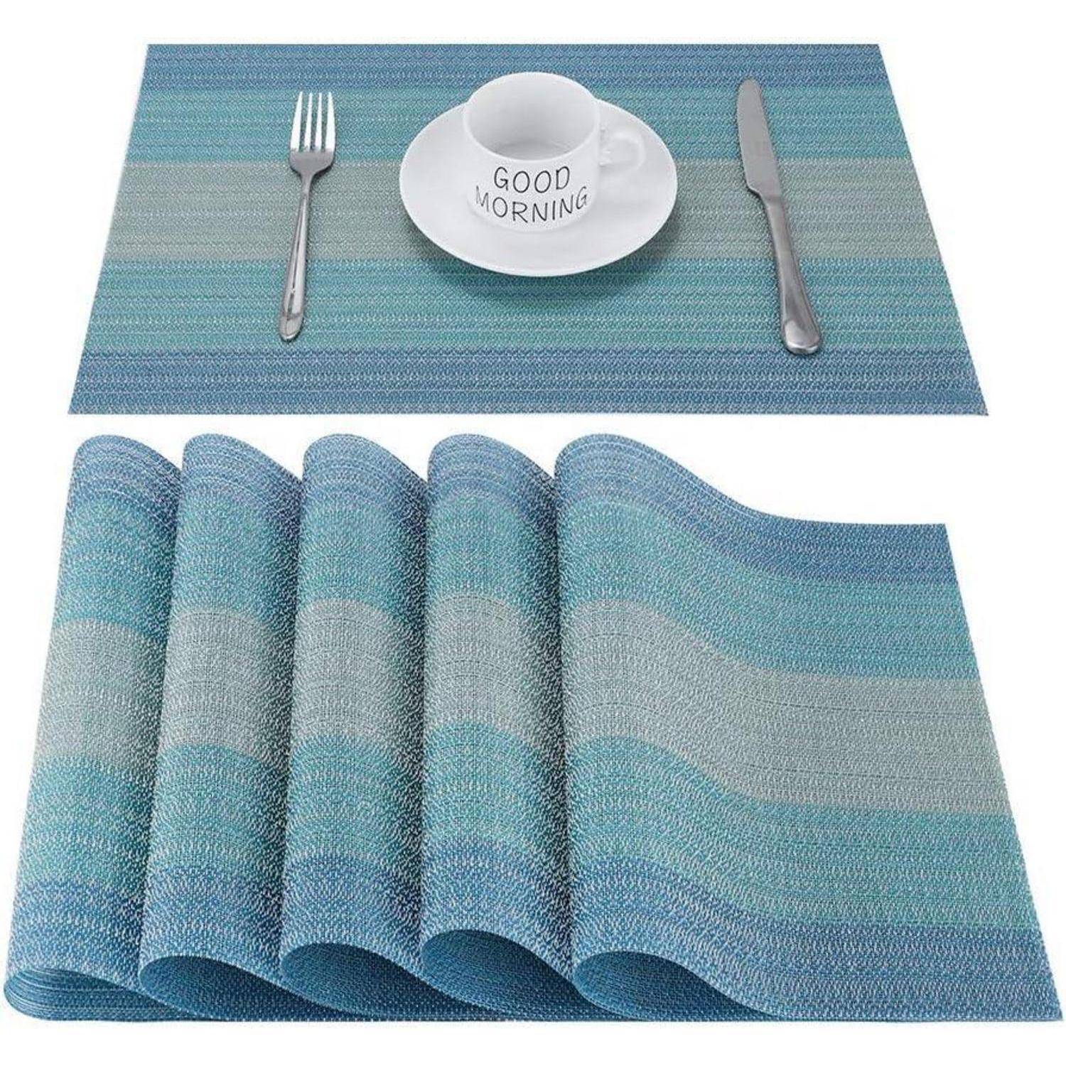 Ein blau gewebter Platzdeckchen wird gezeigt mit einer Tasse und Untertasse, einer Gabel und einem Messer. Auf der Tasse steht 