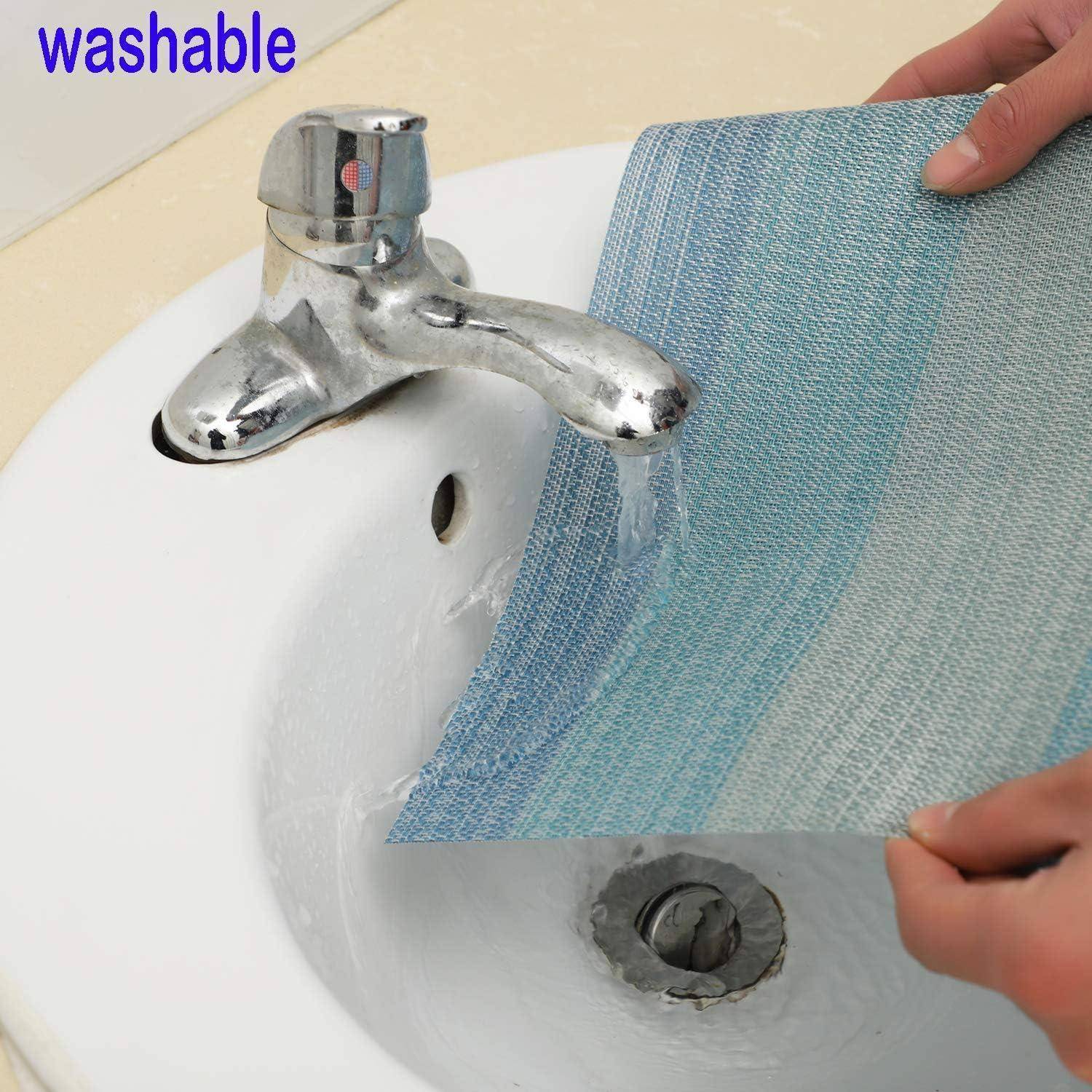 Eine Hand, die einen blau-grauen Stoff unter fließendem Wasser in einem Waschbecken hält und seine Waschbarkeit demonstriert, mit dem Text ‚waschbar' in der oberen linken Ecke.