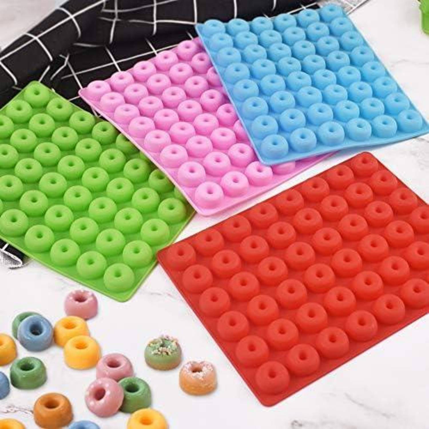 Silikondonutformen in Rot, Grün, Blau und Rosa sind auf einer Theke ausgelegt, mit bunten Donut-Cerealien, die in der Nähe verstreut sind.