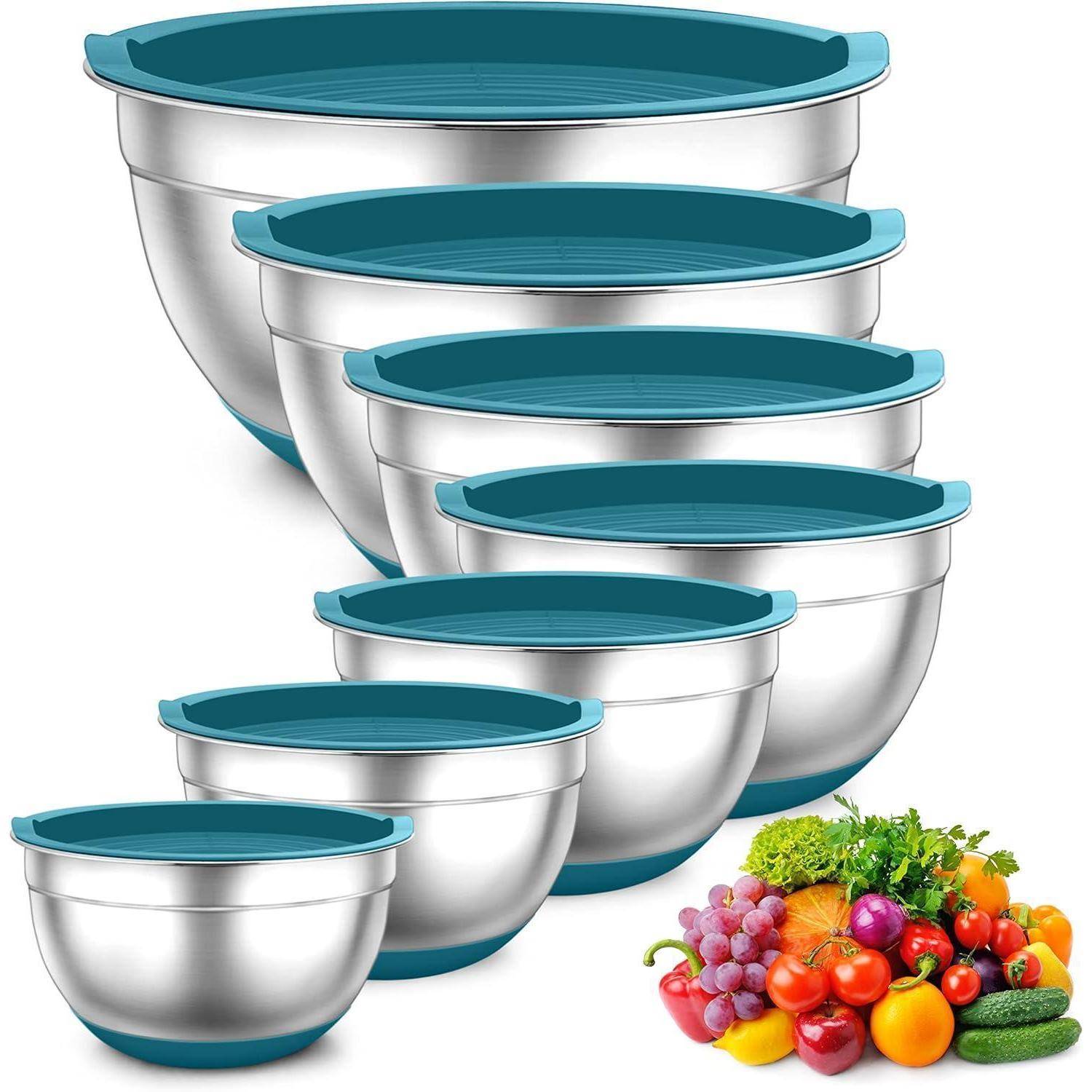 Ein Set aus sechs Edelstahl-Rührschüsseln mit blauen Deckeln, nach aufsteigender Größe angeordnet. Frisches Obst und Gemüse werden in der Nähe präsentiert.