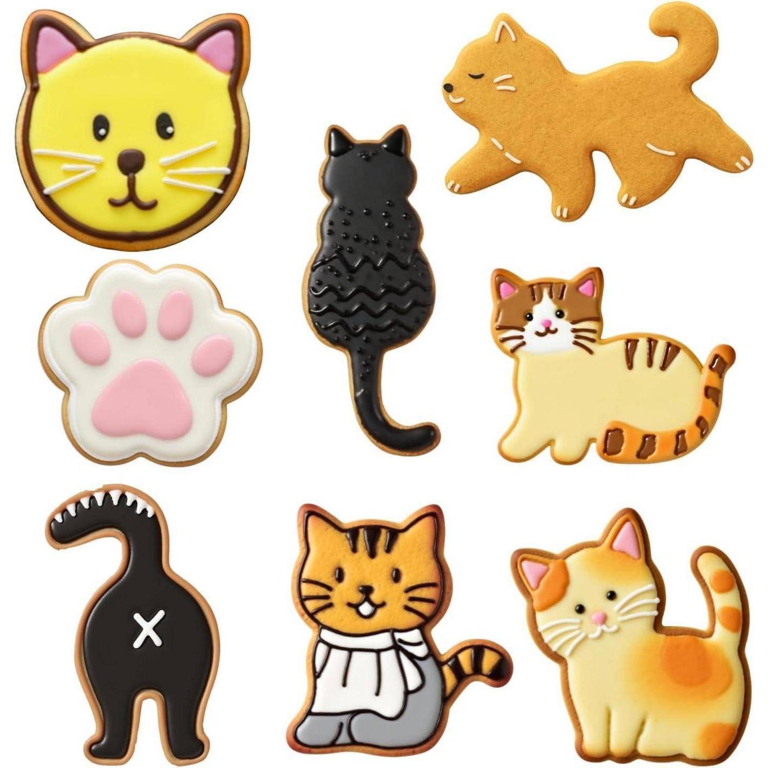 Dekorative Kekse in Form von Katzen und Pfoten mit verschiedenen Designs und Farben, darunter Gelb, Orange, Braun und Rosa.