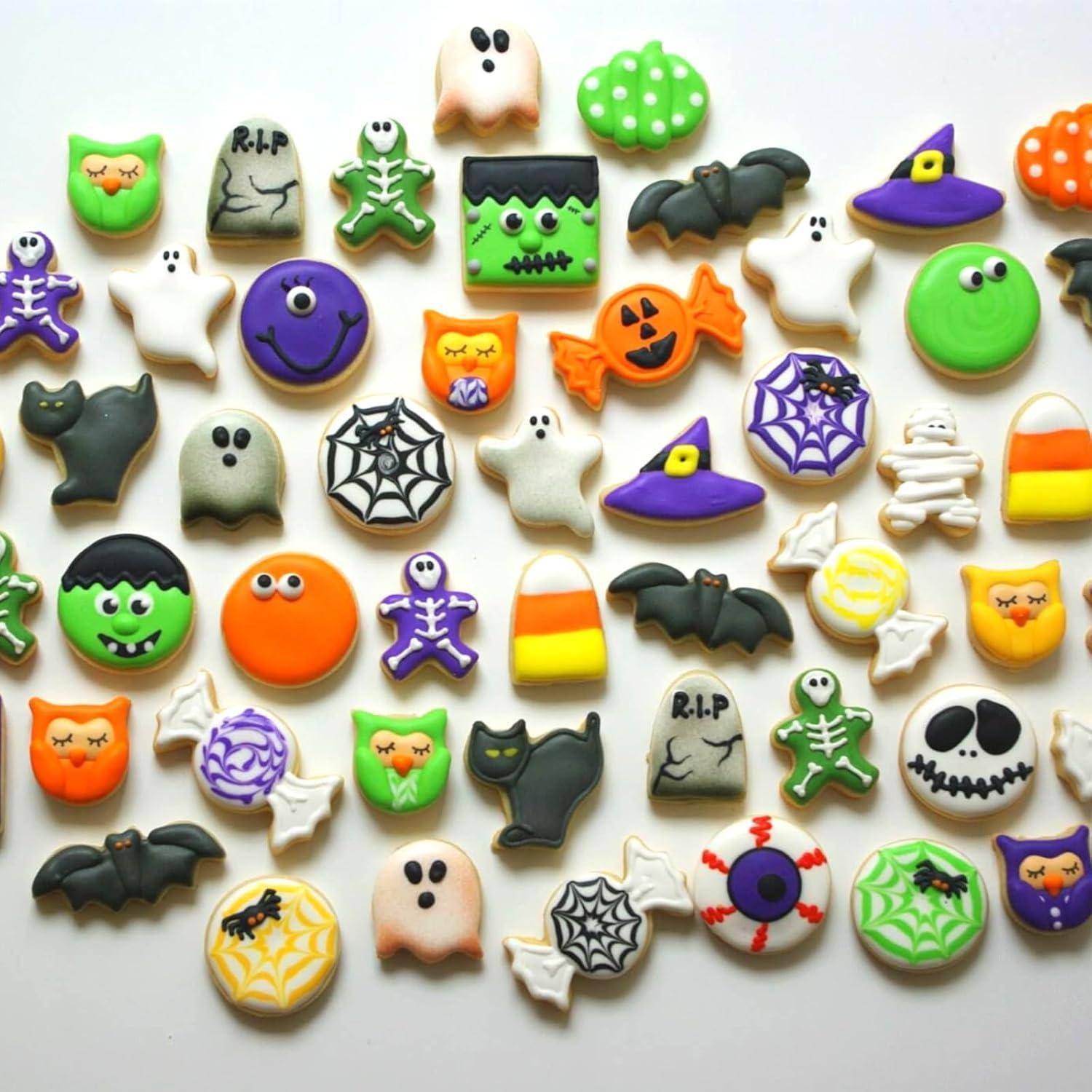 Eine Vielfalt an Halloween-Plätzchen mit Motiven wie Kürbisse, Geister, Spinnen und Hexenhüten, auf einem weißen Hintergrund angeordnet.