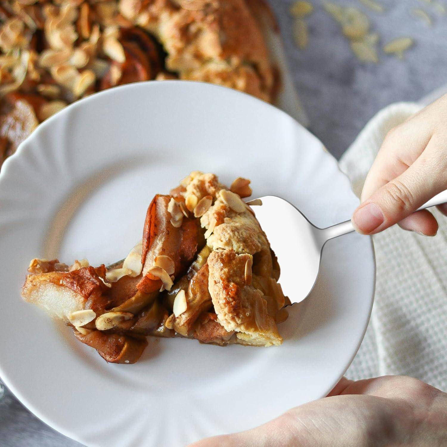 Eine Person hält eine Gabel, um ein Stück Mandel-Apfel-Tarte von einem weißen Teller zu nehmen. Eine weitere Tarte ist im Hintergrund sichtbar.
