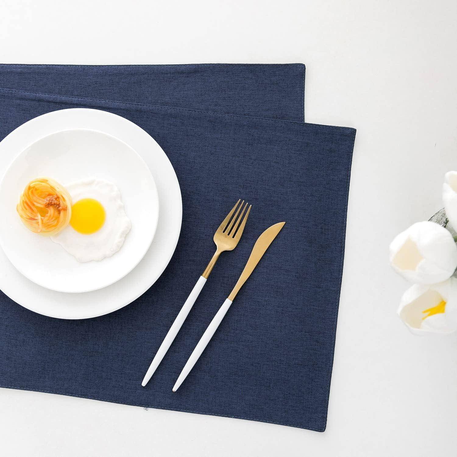 Ein ordentlich angerichtetes Frühstück mit einem Teller mit Spiegelei und Toast auf einem blauen Platzdeckchen, begleitet von einer Gabel und einem Messer.