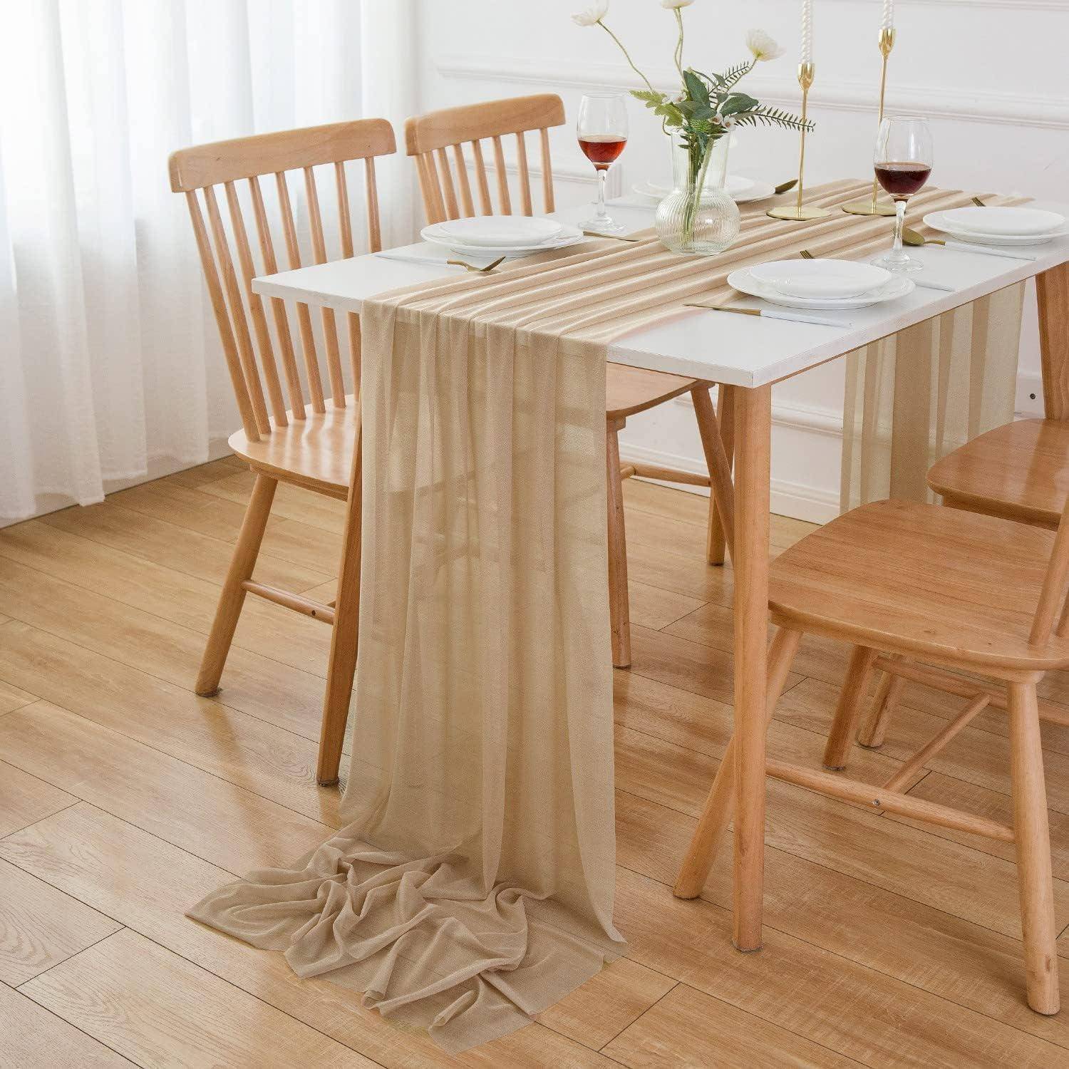 Ein Esstisch für zwei Personen, ausgestattet mit einem beigen Tischläufer, zwei Weingläsern und Tellern, umgeben von Holzstühlen auf einem Holzfußboden.