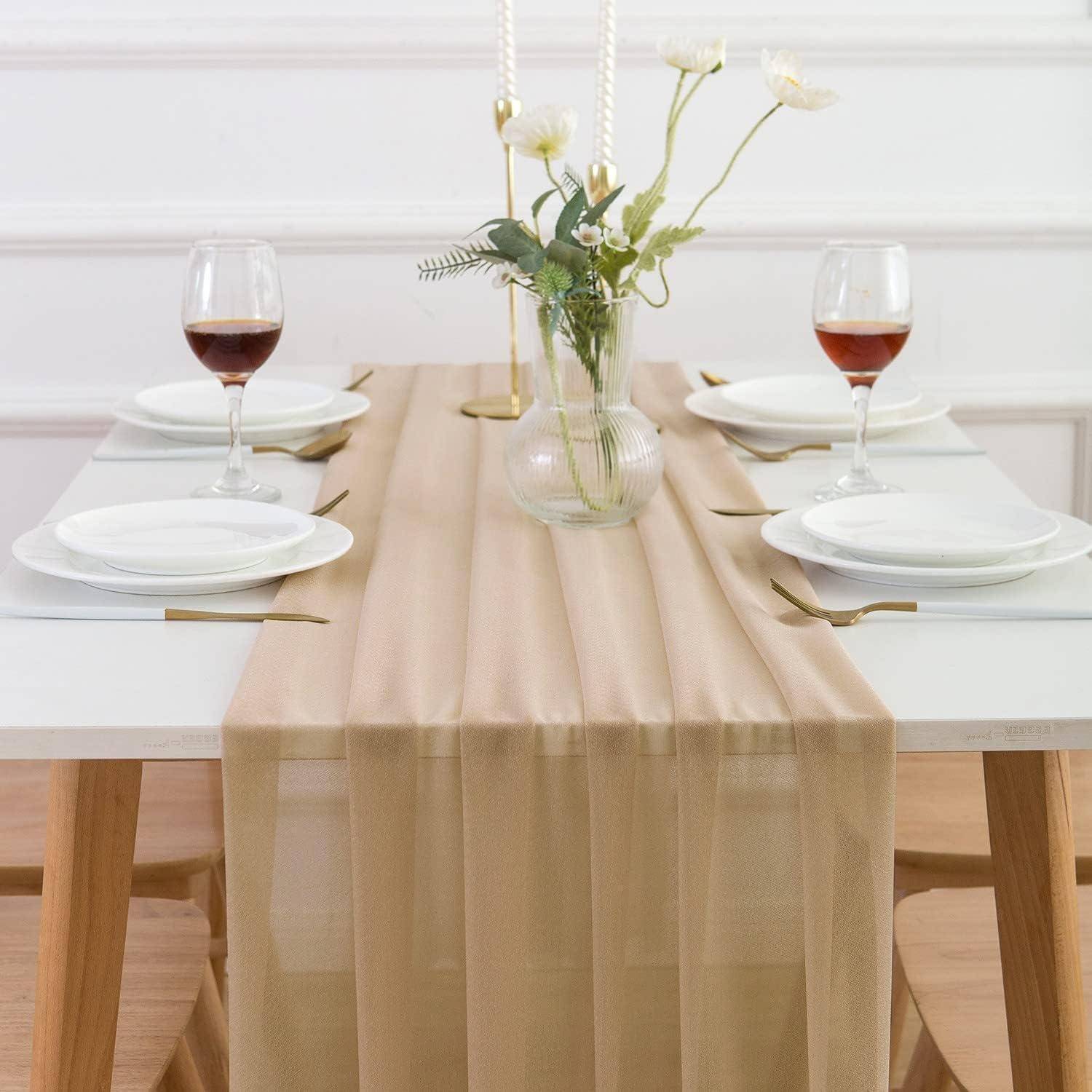 Eleganter Esstisch mit transparentem beigefarbenem Läufer, gedeckt für vier Personen mit weißen Tellern, Weingläsern und einem Blumengesteck in der Mitte.