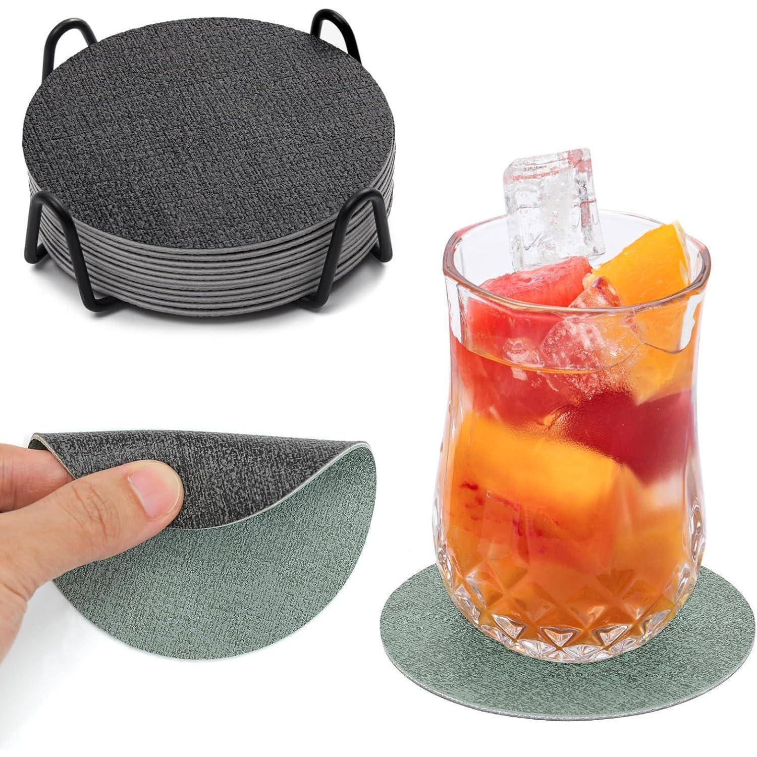Satz aus runden, grauen Stoffuntersetzer mit Halter. Eine Hand hebt einen Untersetzer. Ein Glas mit Getränk und Eis steht auf einem anderen Untersetzer.