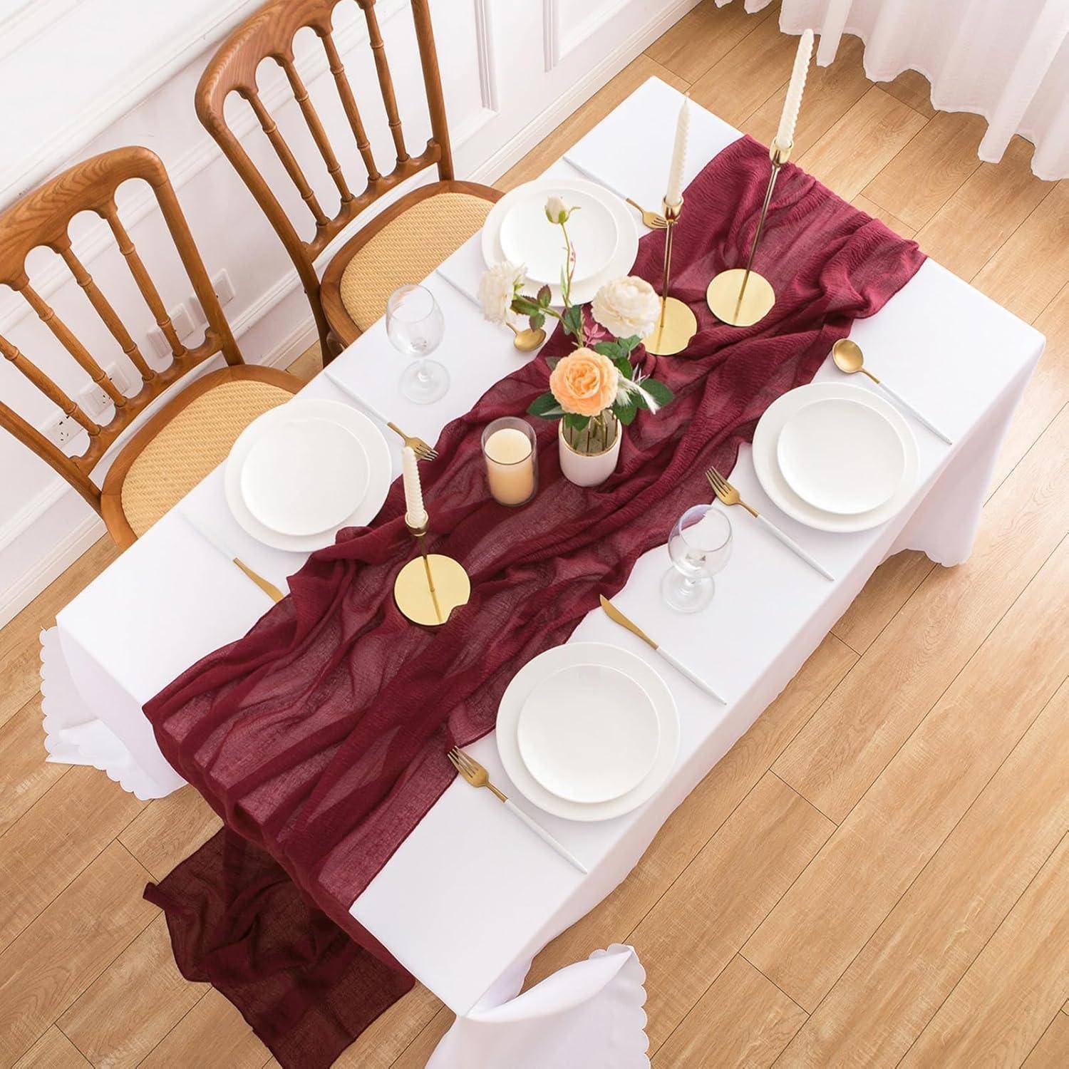Ein elegant gedeckter Esstisch mit einem roten Läufer, weißen Tellern, goldenem Besteck, Weingläsern und einer zentralen Blumenarrangement aus Rosen und Kerzen.