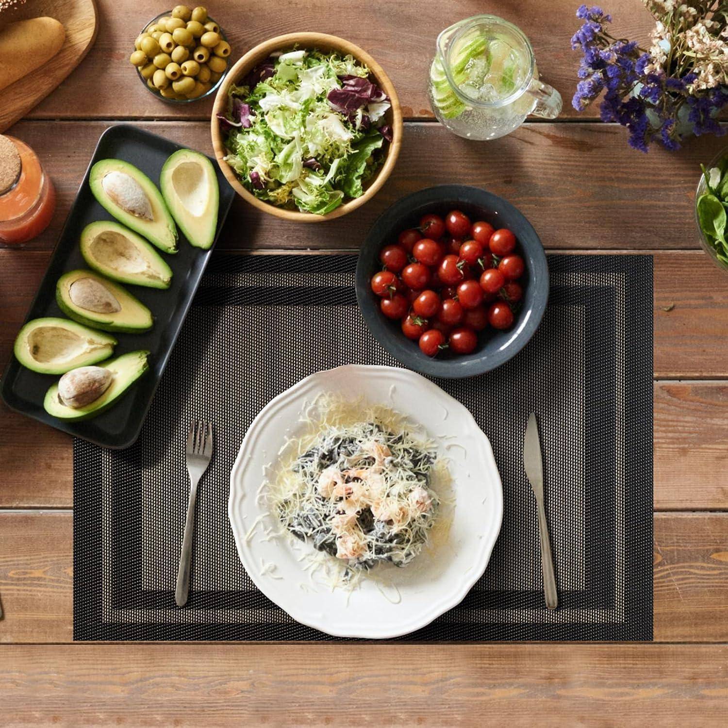 Eine Tischdecke mit einer Pasta-Speise, einem Salat, halbierter Avocado, Tomaten, Oliven, Brot, einem Getränk und Blumen, was auf eine frische Mahlzeit hindeutet.