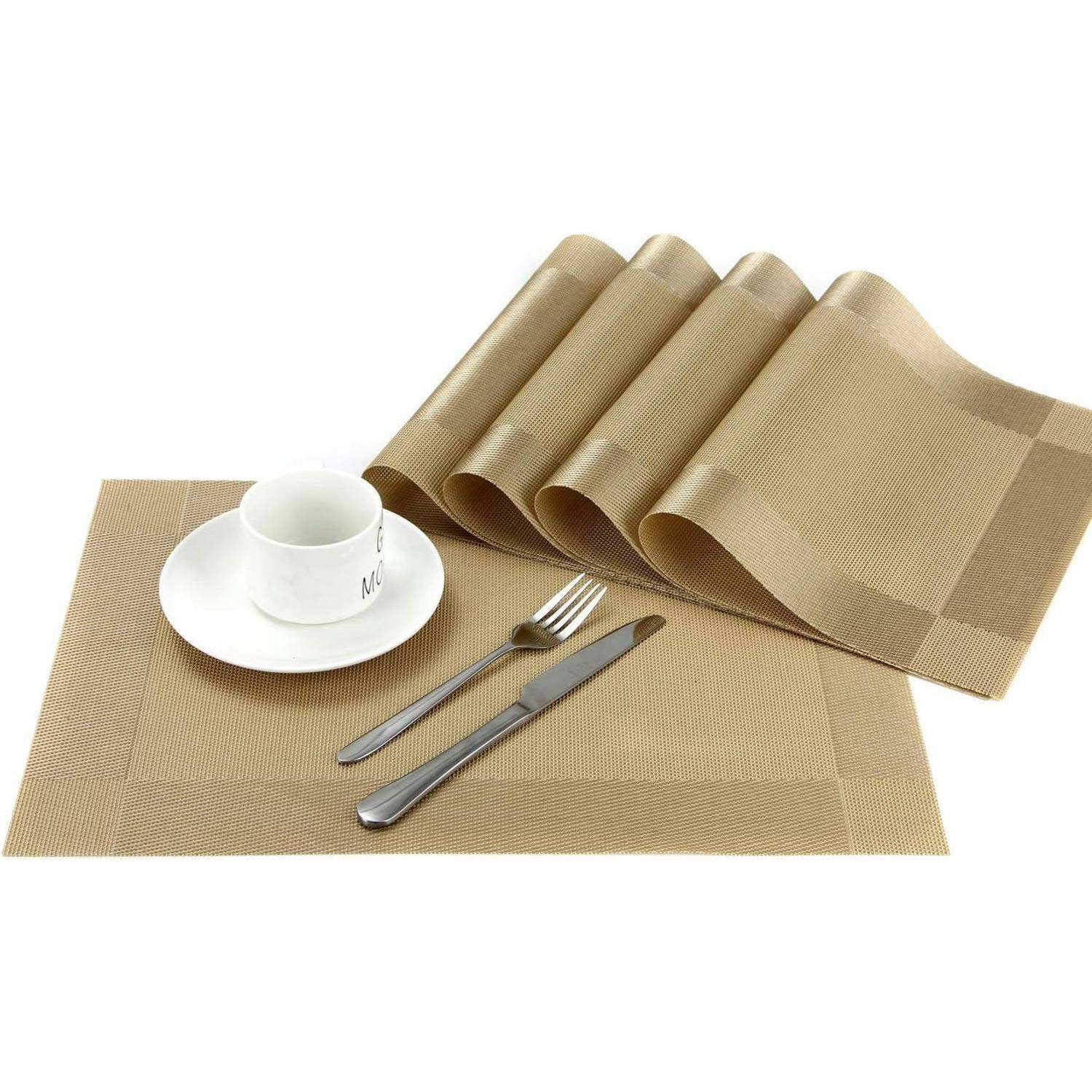 Ein brauner Platzdeckchen-Satz mit zusammengerollter Serviette, Tasse und Untertasse, Messer und Gabel, auf weißem Hintergrund angeordnet.