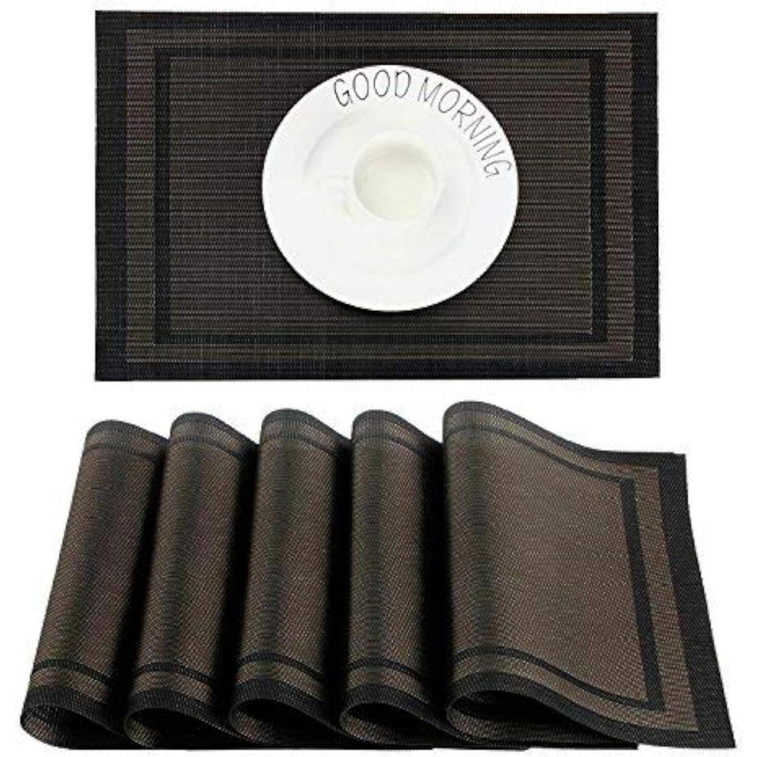 Fünf gewebte schwarze Platzdeckchen, eines mit einem weißen Teller, auf dem die Worte 