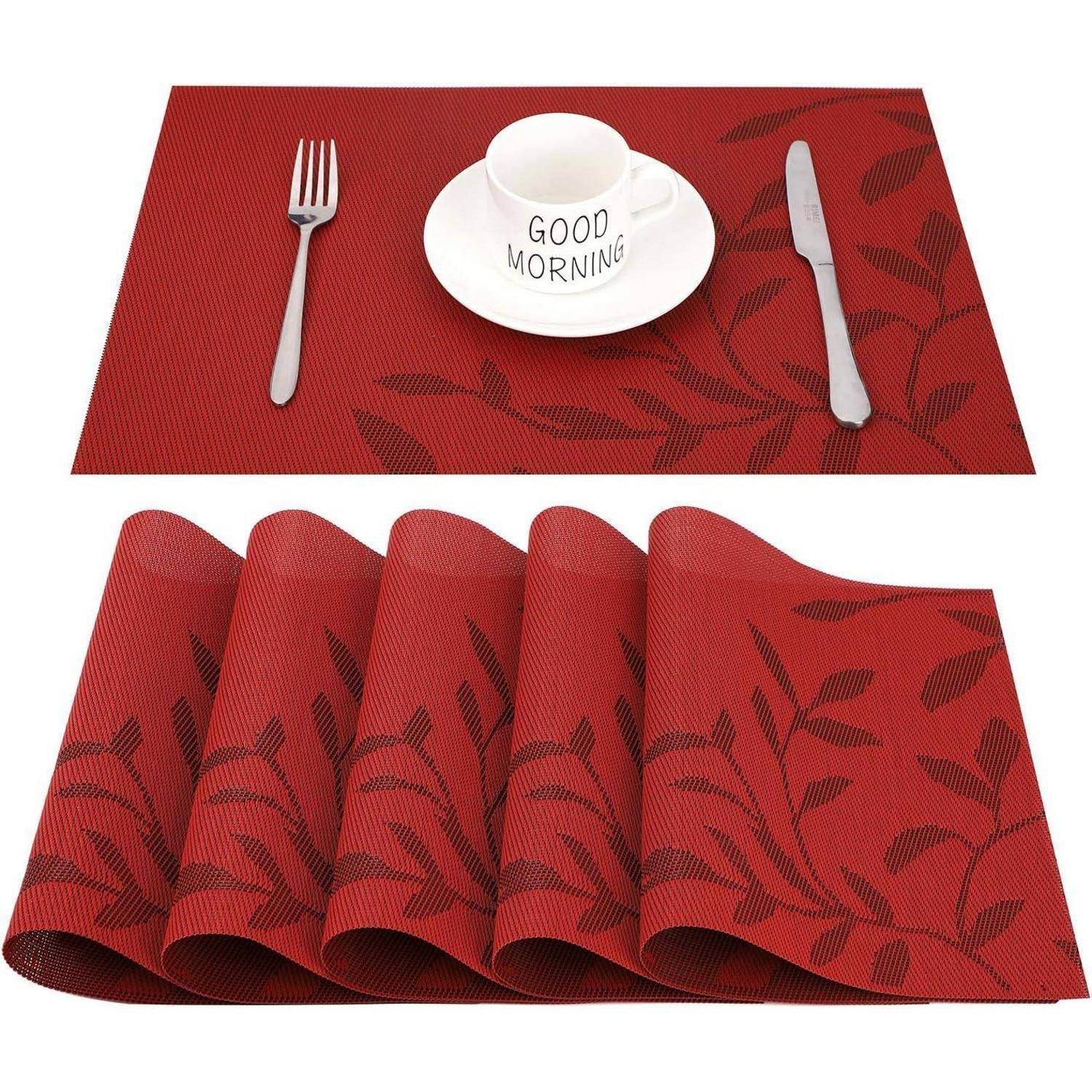 Ein roter Platzdeckchen mit Blattmuster, bestückt mit einer Gabel, einem Messer und einer Tasse auf einem Unterteller, auf dem 