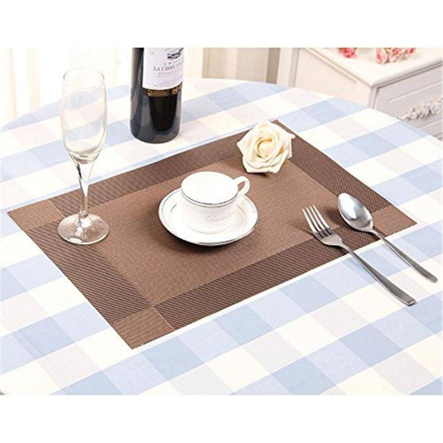 Ein sorgfältig gedeckter Esstisch mit einer Vichy-Karo-Tischdecke, auf dem ein Weinglas, eine Flasche, eine Tasse auf einem Unterteller und Besteck sowie eine Rose platziert sind.