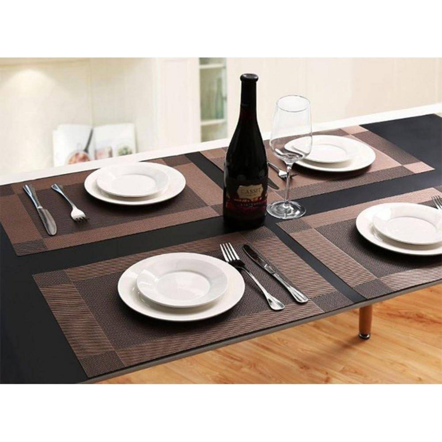Ein Esstisch, gedeckt für vier Personen, mit braunen Tischsets, weißen Tellern, Besteck, einer Weinflasche und einem Glas, auf einem Holzfußboden.