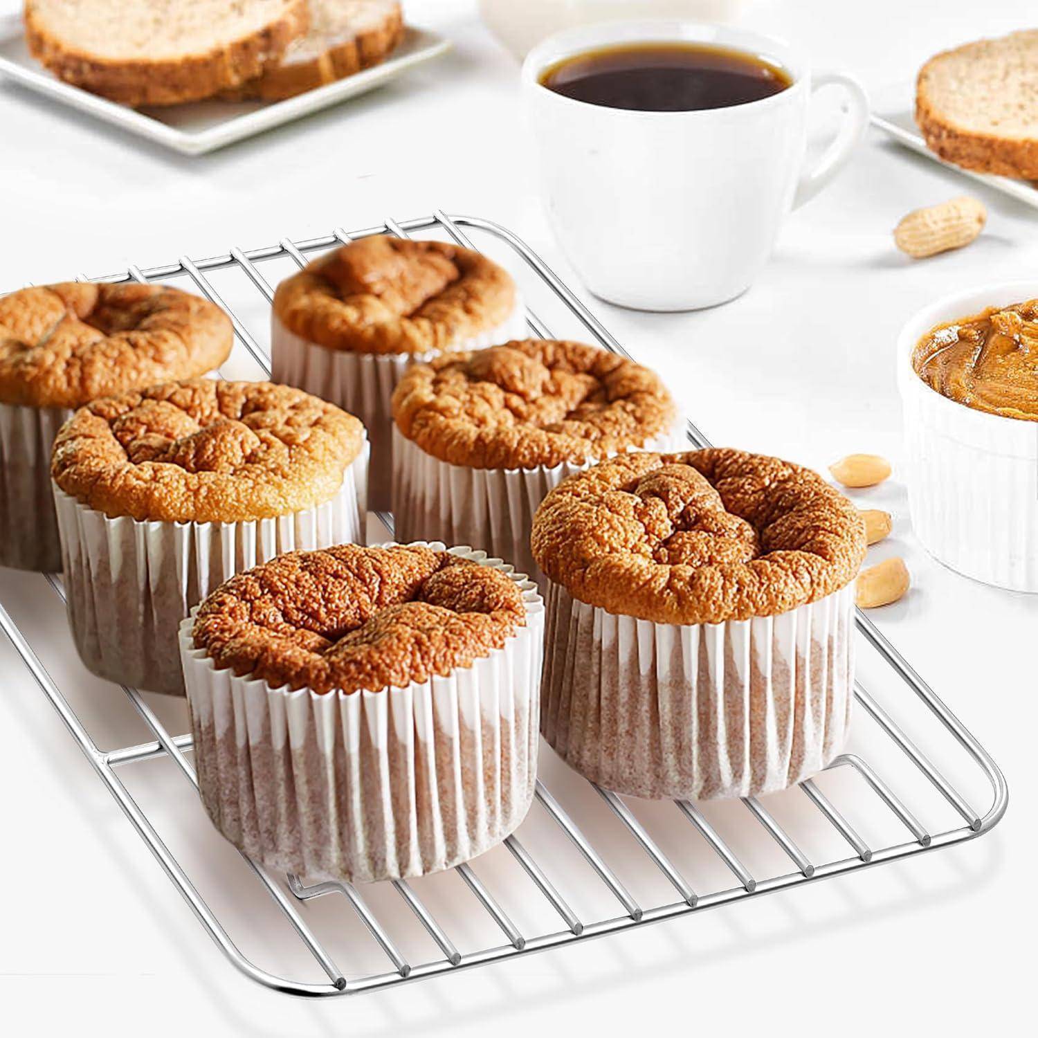 Sechs frisch gebackene Muffins, die auf einem Kuchengitter neben einer Tasse Kaffee und einer Auflaufform mit Nüssen abkühlen, deuten auf eine Frühstückssituation hin.