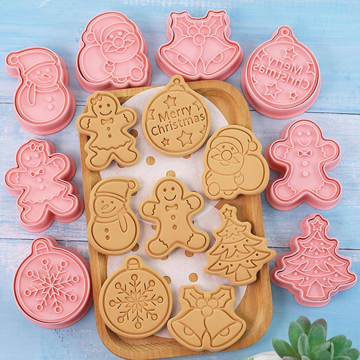 Ausstechformen und gebackene Kekse in Form von Lebkuchenmännchen, Schneemännern und Weihnachtsbäumen, die auf einem Holztablett angeordnet sind.