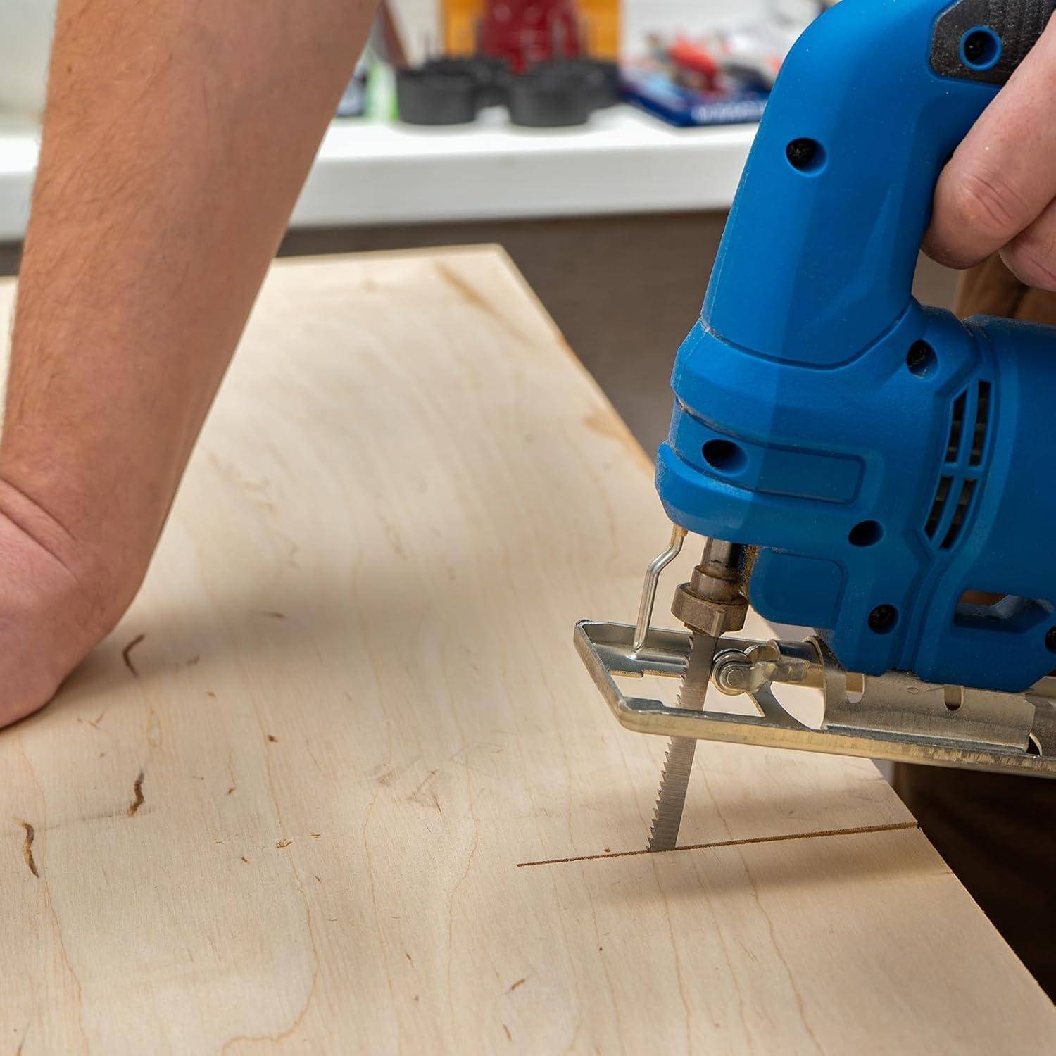 Eine Person, die eine blaue elektrische Stichsäge verwendet, um ein Holzbrett auf einer Werkbank zu zersägen und dabei einen Holzbearbeitungsprozess demonstriert.