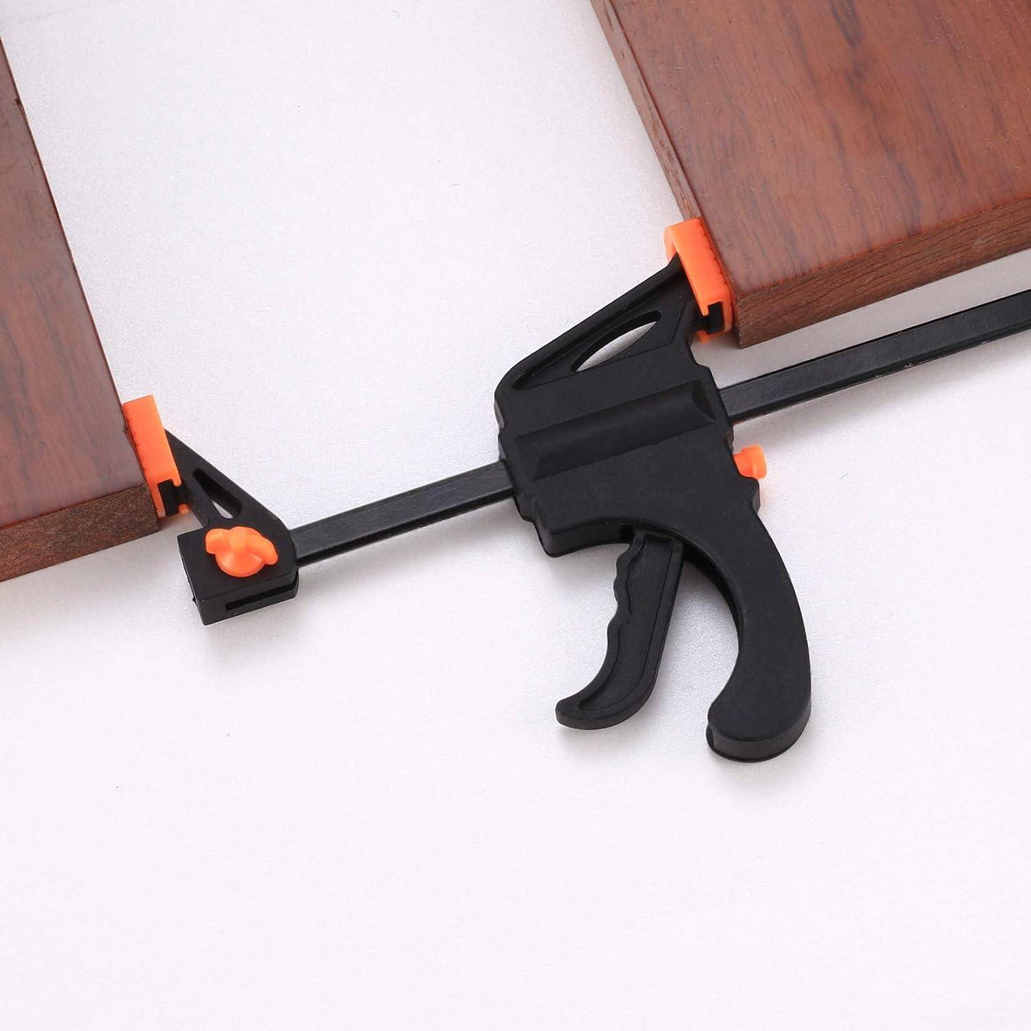 Eine schwarze und orangefarbene Schraubzwinge, die zwei Holzstücke in einem rechten Winkel miteinander befestigt.