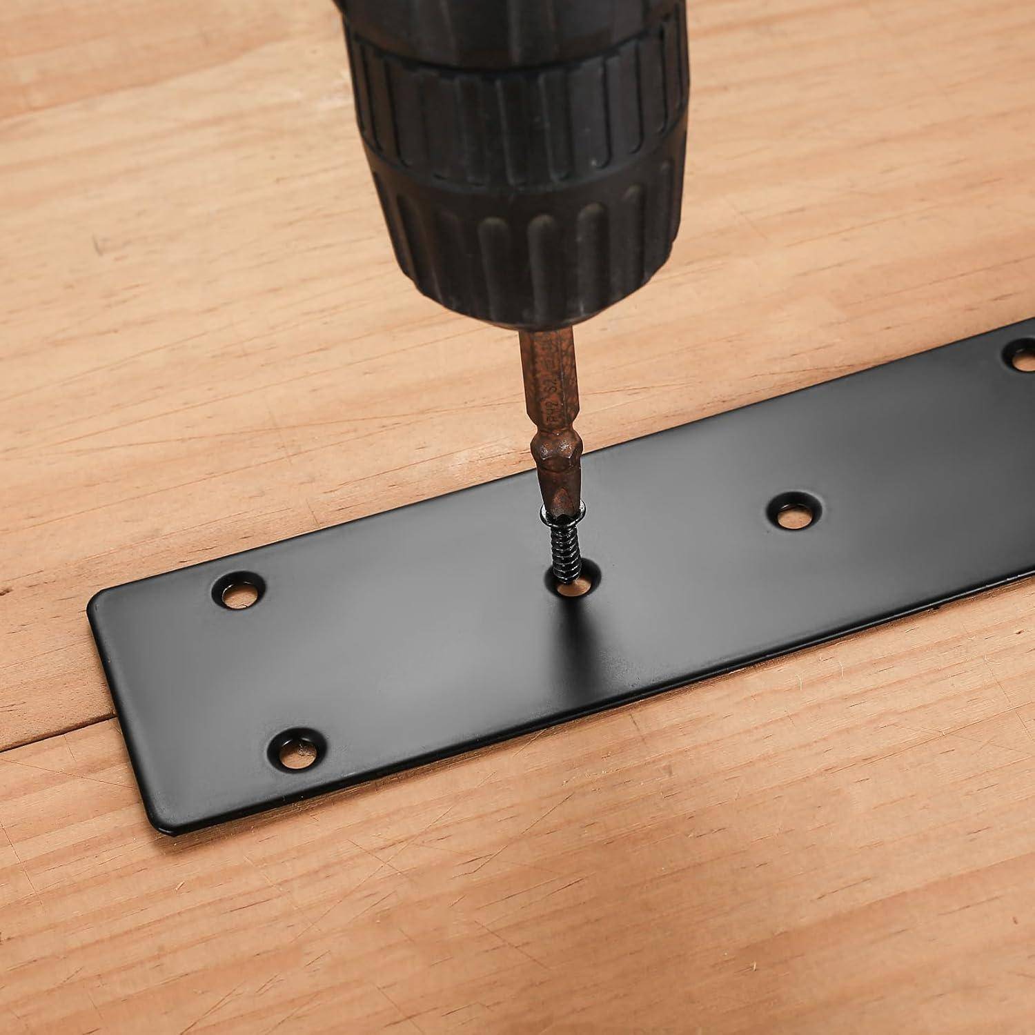 Eine Bohrmaschine schraubt eine Schraube in eine schwarze Metallhalterung auf einer Holzoberfläche und befestigt sie. Vier Löcher in der Halterung für zusätzliche Schrauben.