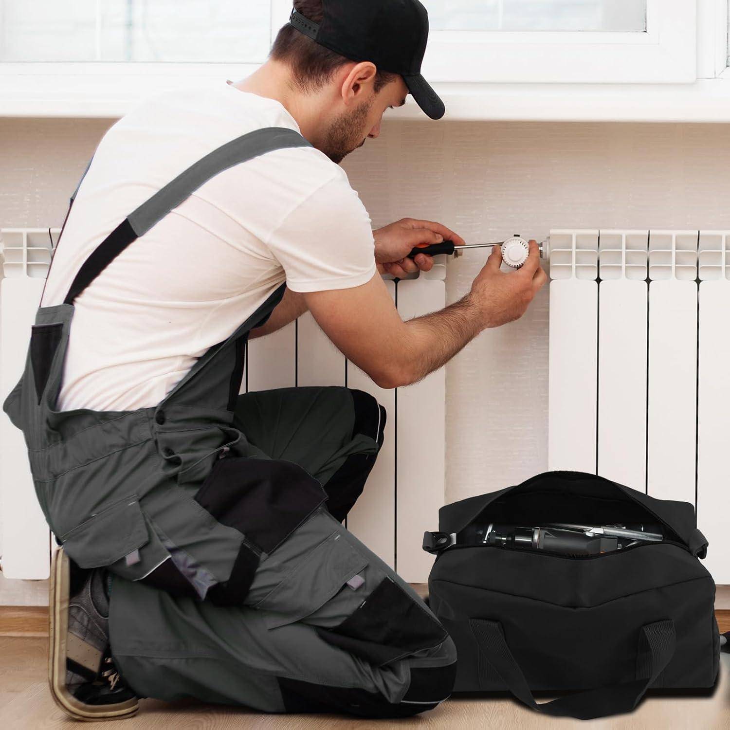 Ein Techniker in Uniform kniet, um einen Heizkörper zu installieren oder zu reparieren und dabei ein Werkzeug zu benutzen. Eine Werkzeugtasche mit verschiedenen Werkzeugen liegt neben ihm auf dem Boden.