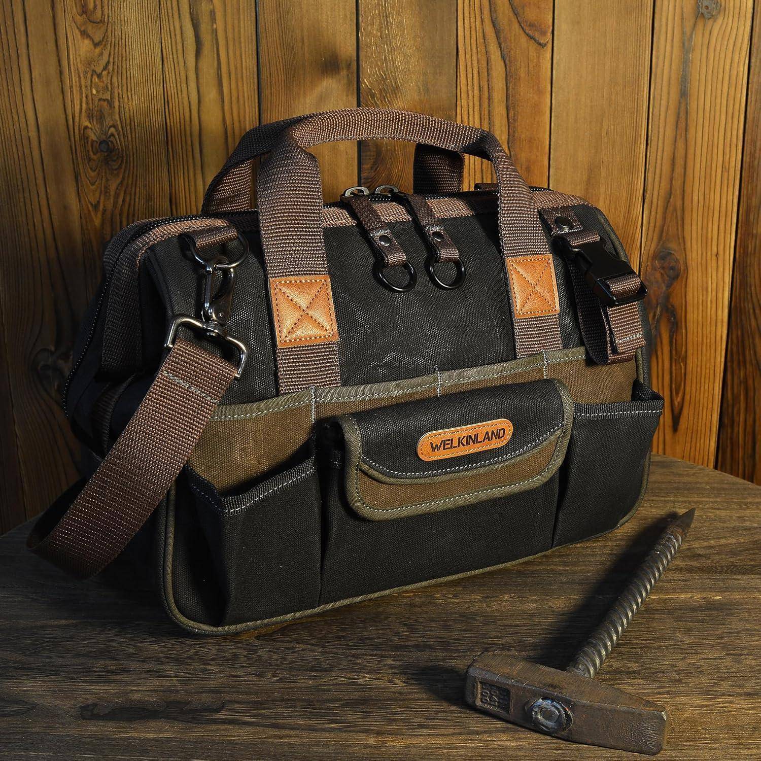 Eine strapazierfähige Werkzeugtasche in Schwarz und Braun mit mehreren Taschen, beschriftet mit 'Welkinland', liegt auf einer Holzoberfläche neben einem Metallhammer.