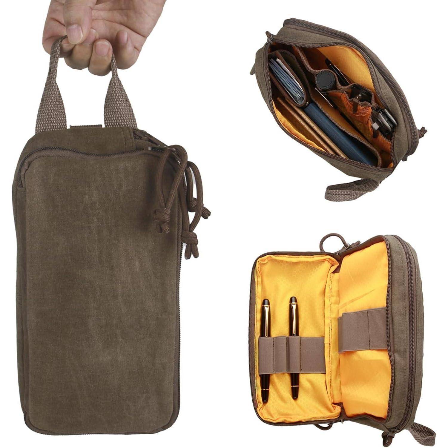 Eine Hand hält eine braune Reißverschlusstasche mit einem Griff. Die Tasche öffnet sich und zeigt mehrere Fächer, die Stifte und ein Telefon ordentlich sortieren.