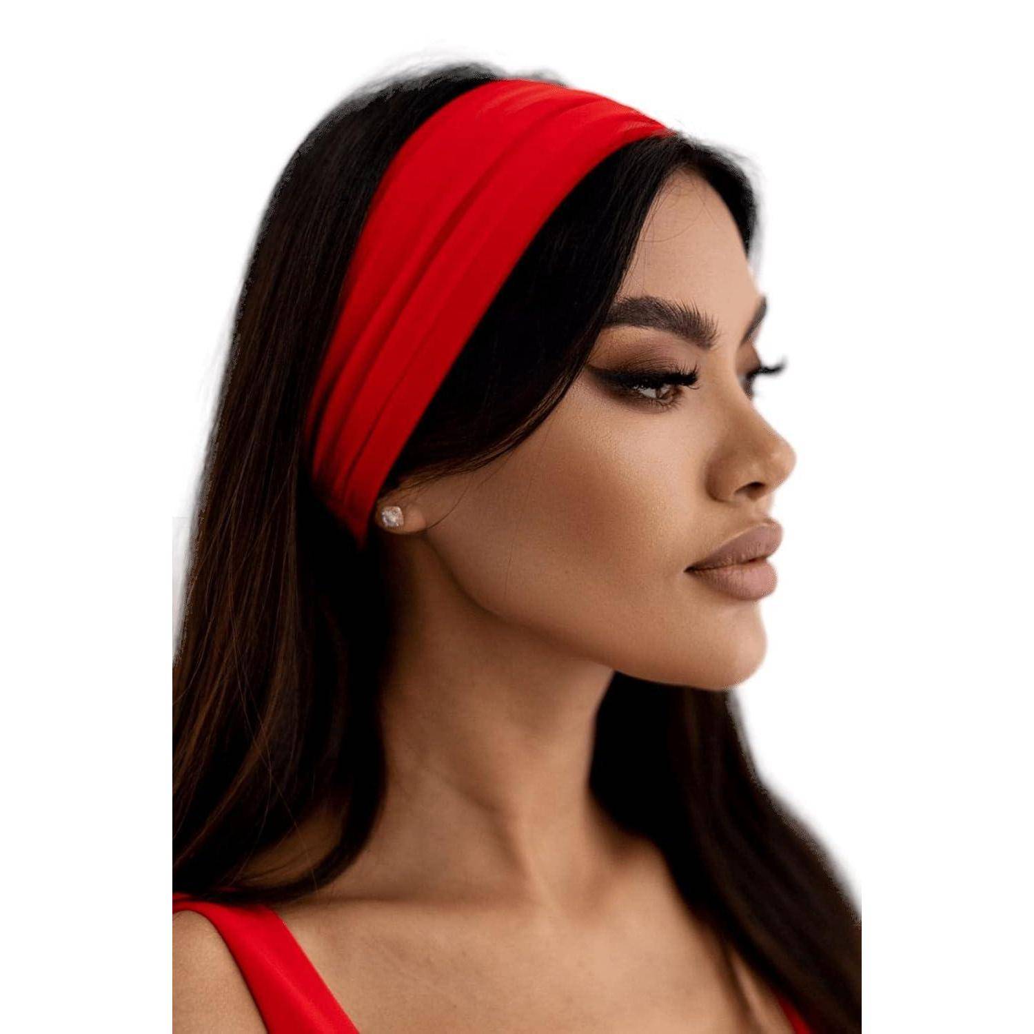 Eine Person mit geradem dunklem Haar, die ein rotes Haarband trägt, blickt zur Seite. Sie trägt ein rotes Oberteil und einen einzelnen Ohrstecker.