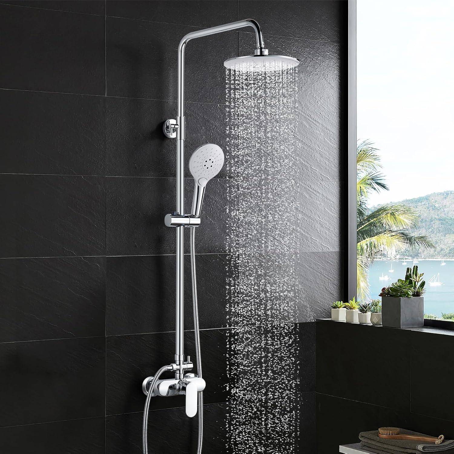 Eine moderne Dusche mit einem großen, runden Duschkopf lässt einen gleichmäßigen Wasserstrahl in einem eleganten, dunkel gekachelten Badezimmer herabfließen. Ein Fenster gibt den Blick auf einen Baum frei.