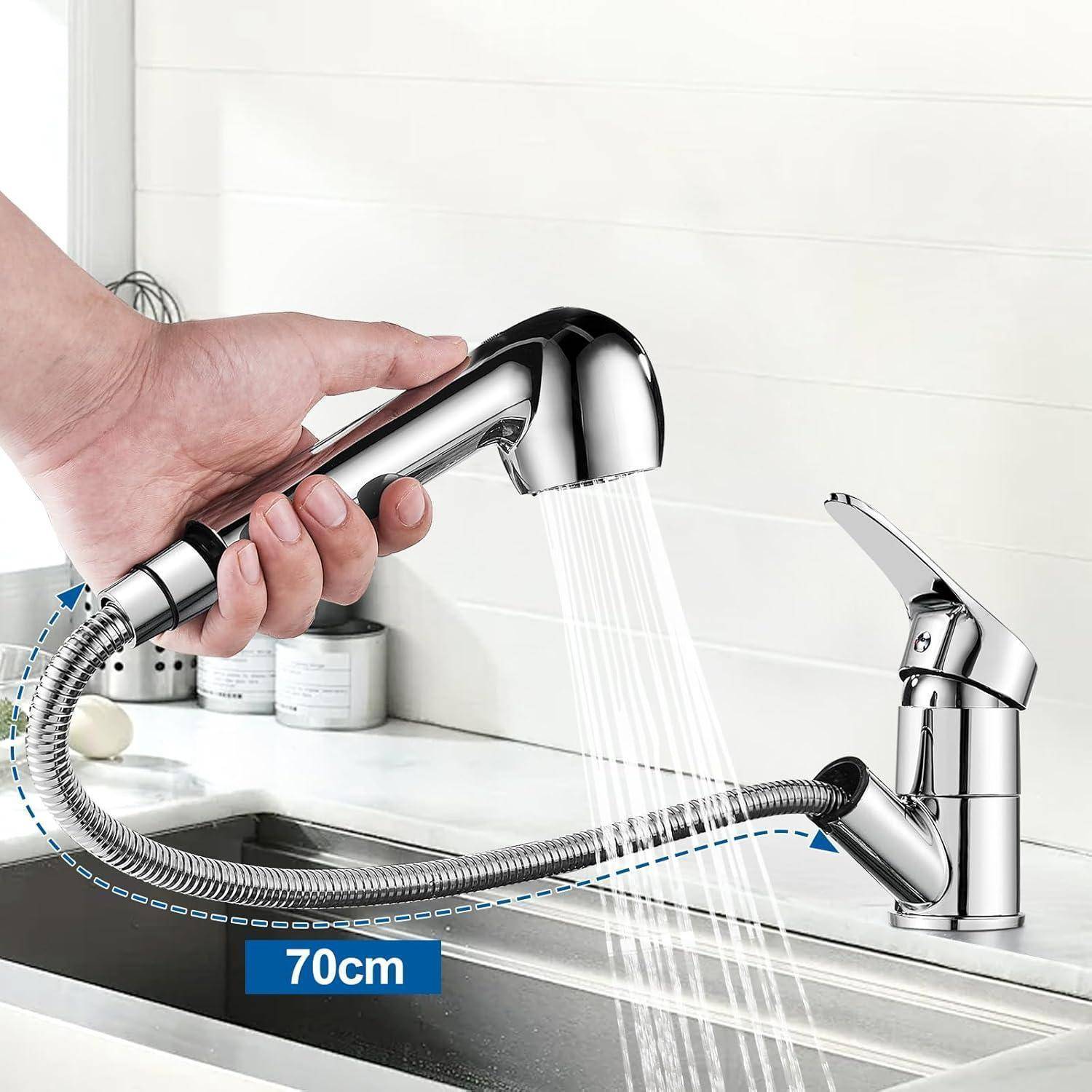Eine Hand zieht eine flexible Küchenarmatur-Brause über einem Waschbecken heraus und demonstriert eine Ausdehnung von 70 cm. Weiße Fliesen und Behälter sind im Hintergrund sichtbar.