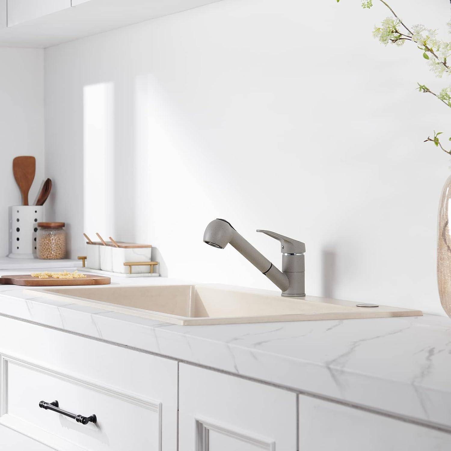 Eine moderne Küchenspüle mit einem eleganten Wasserhahn, weißen Schränken und einer Marmorarbeitsplatte. Dekorative Gläser, ein Stapel Schüsseln und eine Pflanze sind zu sehen.