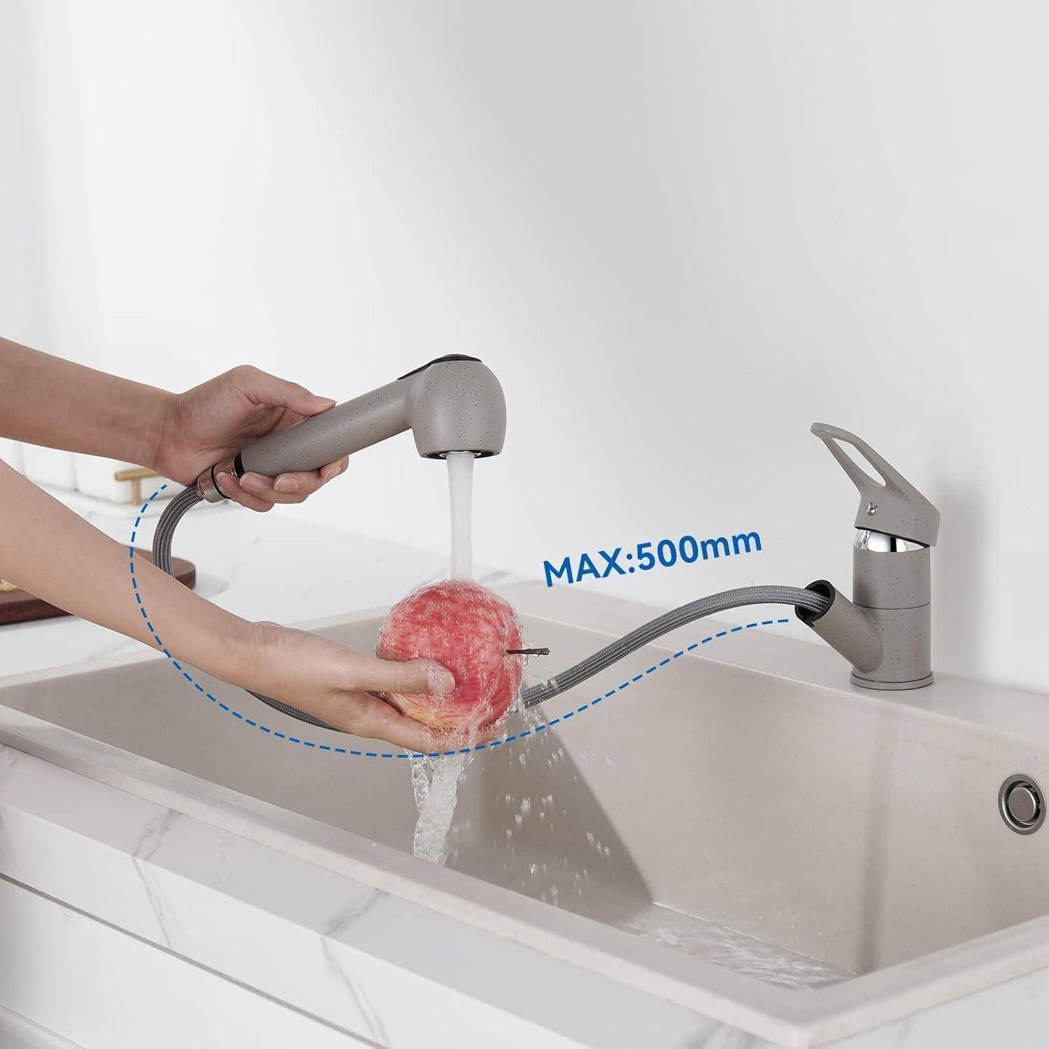 Eine Person verwendet einen Ausziehbarer Wasserhahn, um einen roten Apfel in einem Küchenbecken zu waschen. Der Wasserhahn erstreckt sich bis zu 500 mm, wie durch einen Pfeil gekennzeichnet.