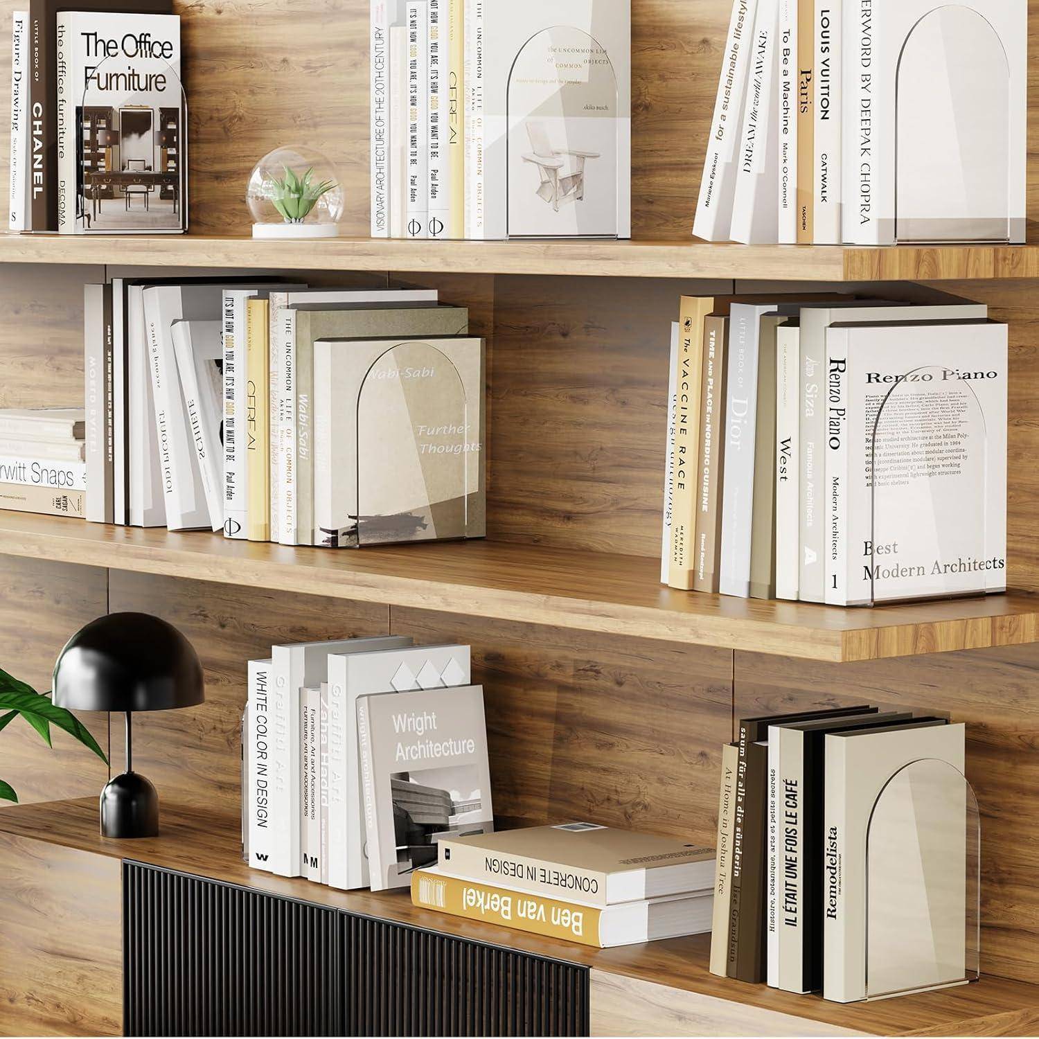 Ein Bücherregal aus Holz, gefüllt mit verschiedenen Büchern über moderne Architektur und Design, eine kleine Uhr, Topfpflanzen und eine Lampe in der Nähe.