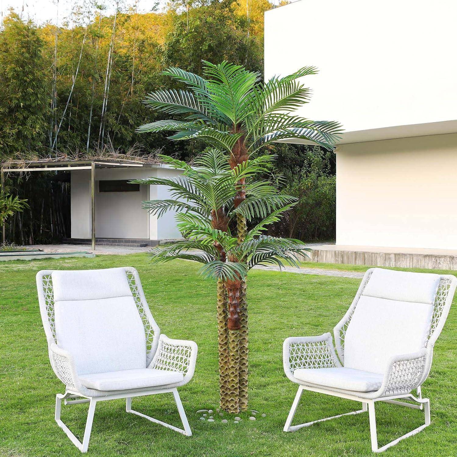 Zwei weiße Stühle stehen auf einem gepflegten Rasen neben einer kleinen Palme, mit einem modernen weißen Gebäude und Bambus im Hintergrund.